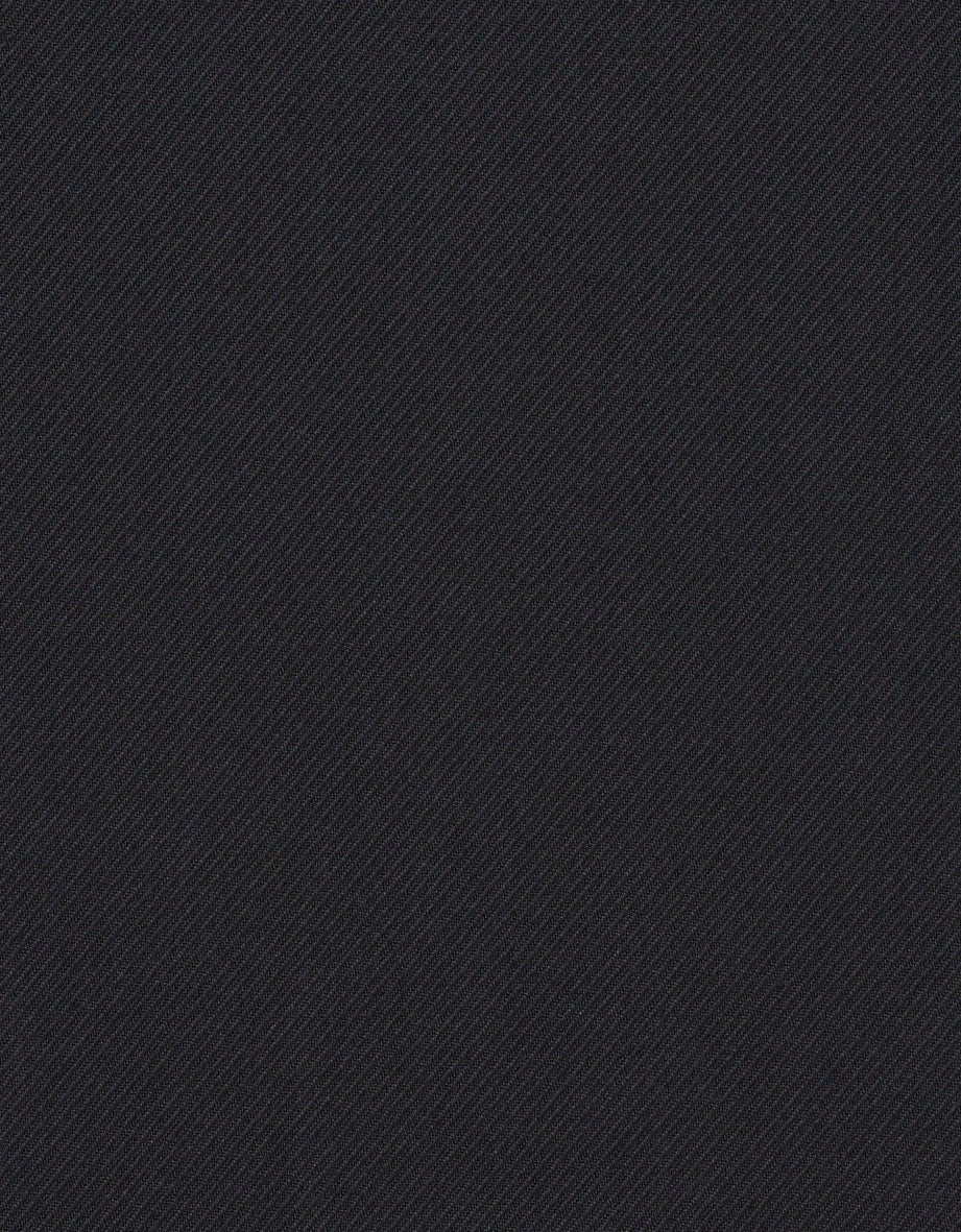 Elegantes Modelbild: Schwarzer Mantel, grauer Pullover, weiße Hose, braune Loafers, entspanntes Posing.