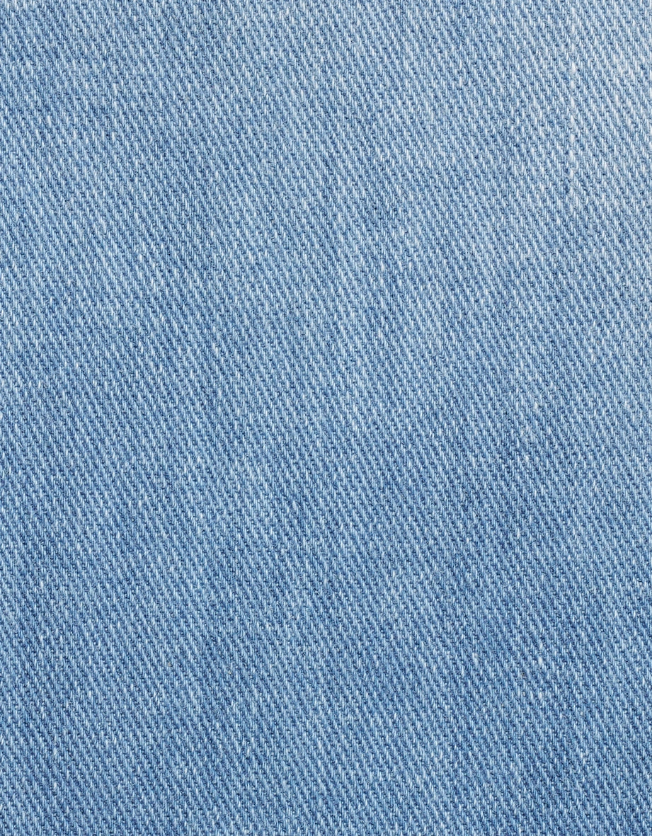 Hellblauer Denimstoff in Nahaufnahme, zeigt die Textur und Webart des Materials.