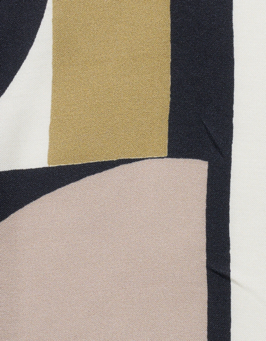 Bluse mit geometrischem Muster in Beige, Blau und Oliv, legeres Modelbild, Hand in Hosentasche.