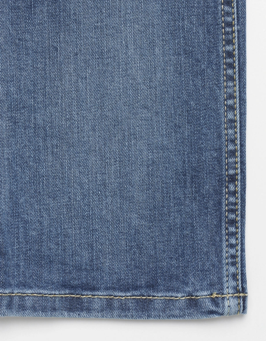 Blauer bugatti Jeansstoff mit gelber Naht, Detailaufnahme.