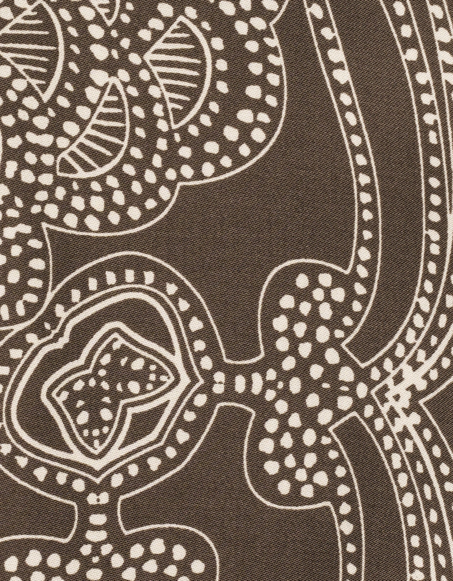 Braunes, gemustertes Textil mit weißen geometrischen Formen, Detailaufnahme.