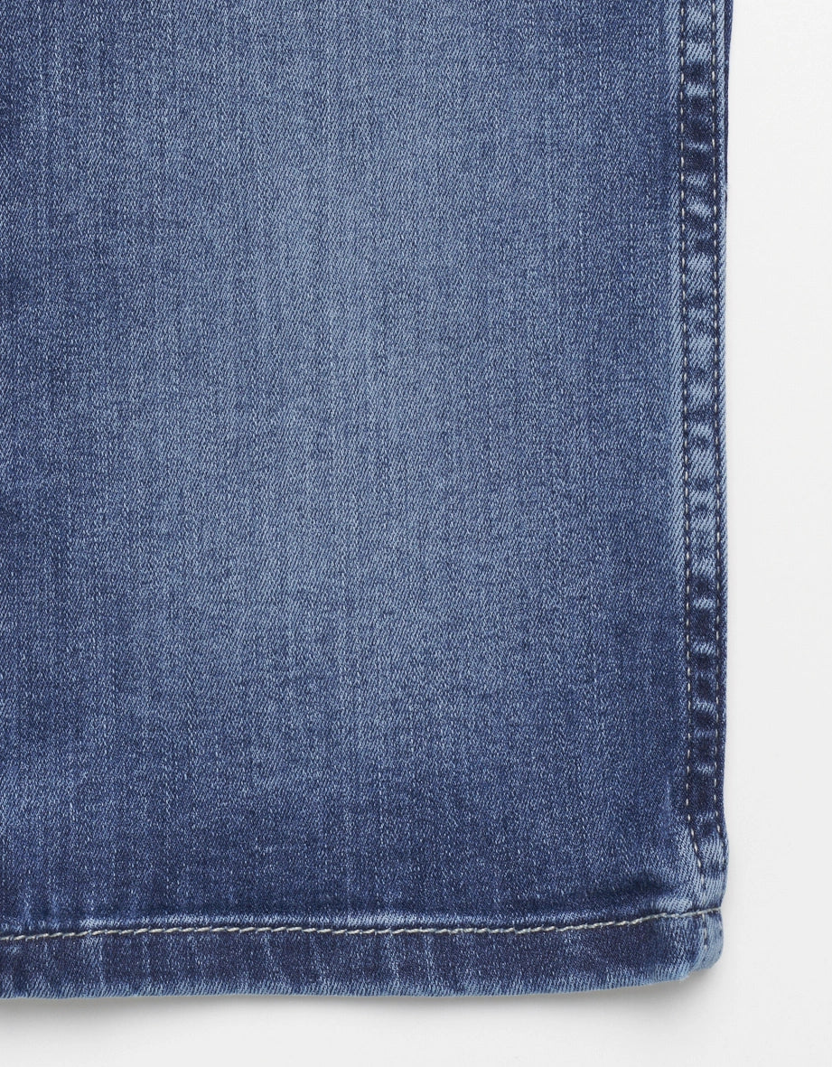 Jeans in medium blue with white shirt, casual style, detail view.