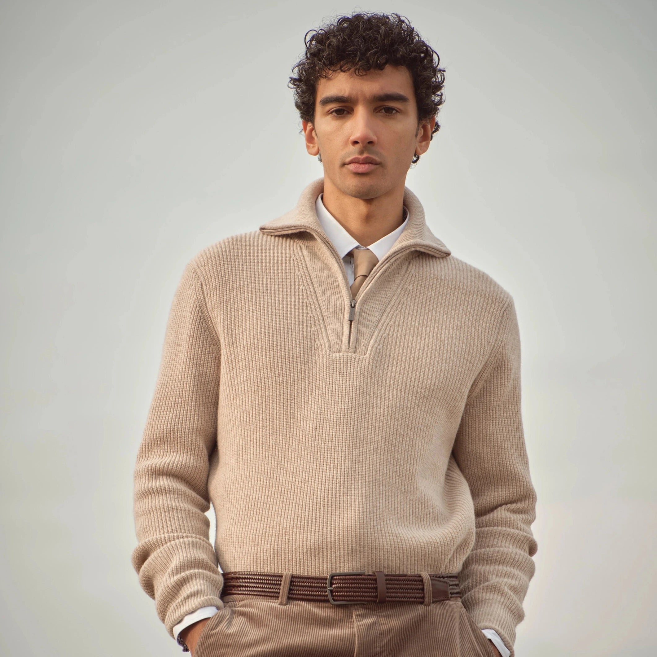 Mann trägt beigefarbenen bugatti Strickpullover mit halbem Zipper über Hemd und Krawatte, kombiniert mit brauner Cordhose und Gürtel – eleganter Herrenlook der Herbst/Winter-Kollektion 2025 im Venetian Chic.