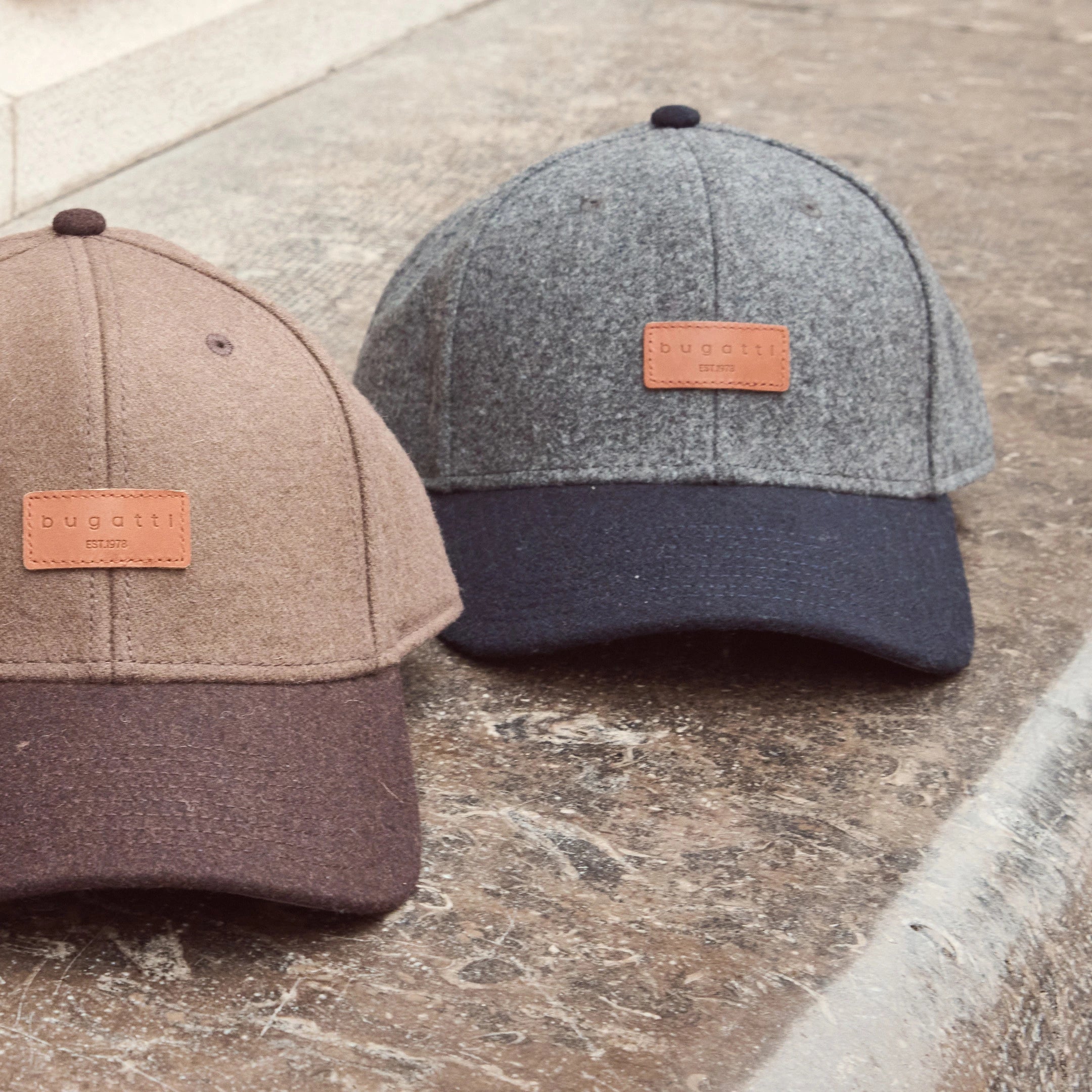 Zwei bugatti Caps aus Wollmix in Taupe und Grau mit Leder-Logo-Patch, Teil der Herren Herbst/Winter-Kollektion 2025 – moderne Accessoires im Venetian Chic.
