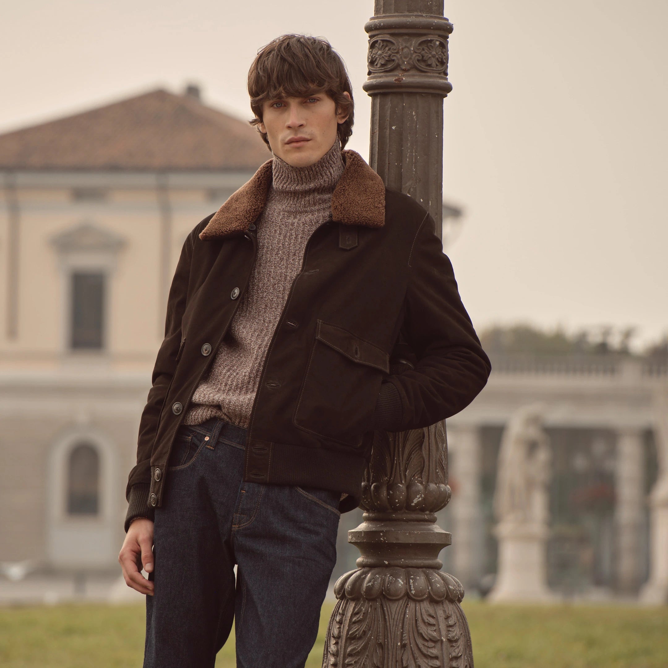 Mann trägt dunkelbraune bugatti Jacke mit Fellkragen über Strickpullover und Jeans, Teil der Herren Herbst/Winter-Kollektion 2025 – stilvoller Casual Look im Venetian Chic.
