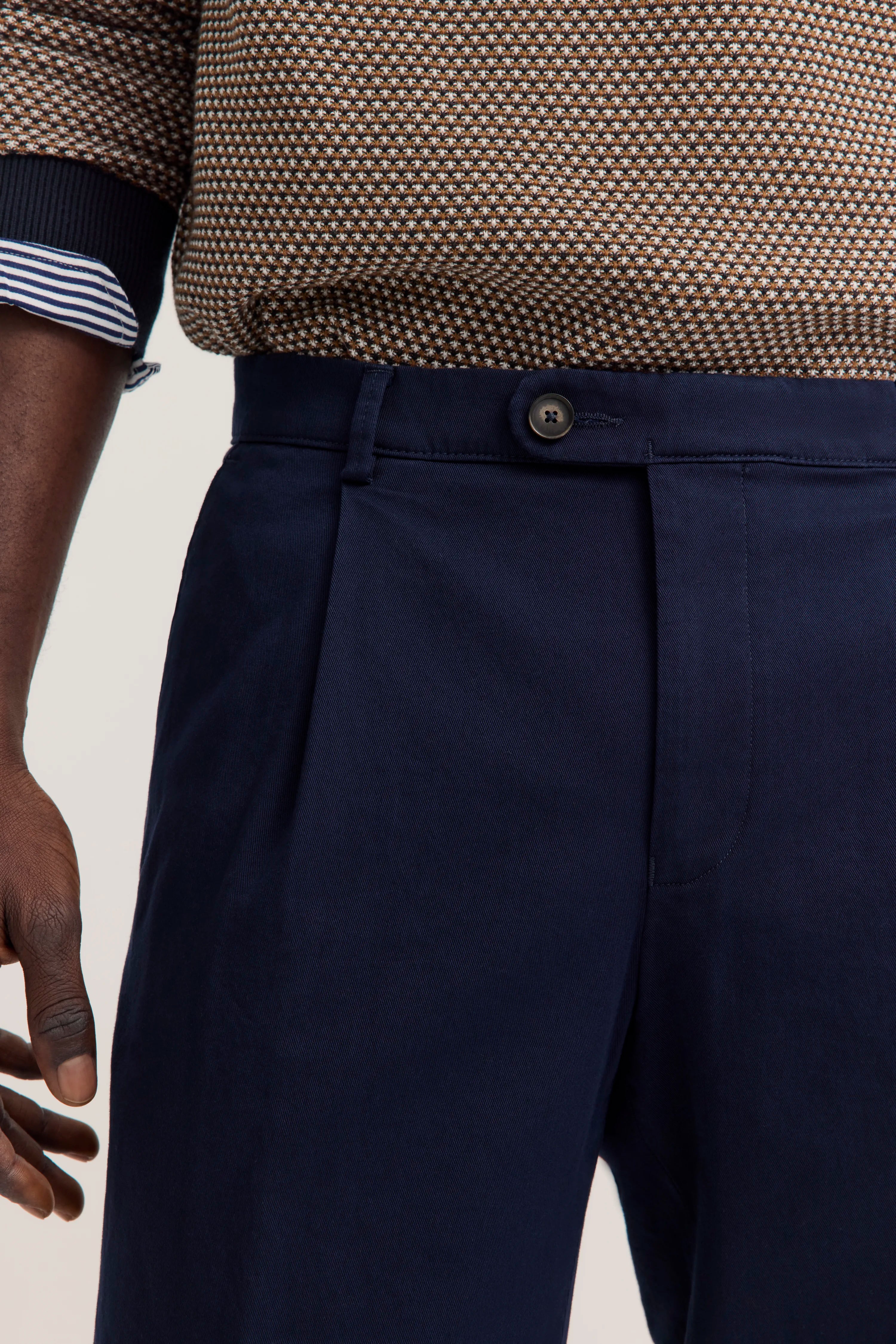 Büstenbild von bugatti: Braun gemusterter Pullover, dunkelblaue Hose. Eleganter, entspannter Stil.