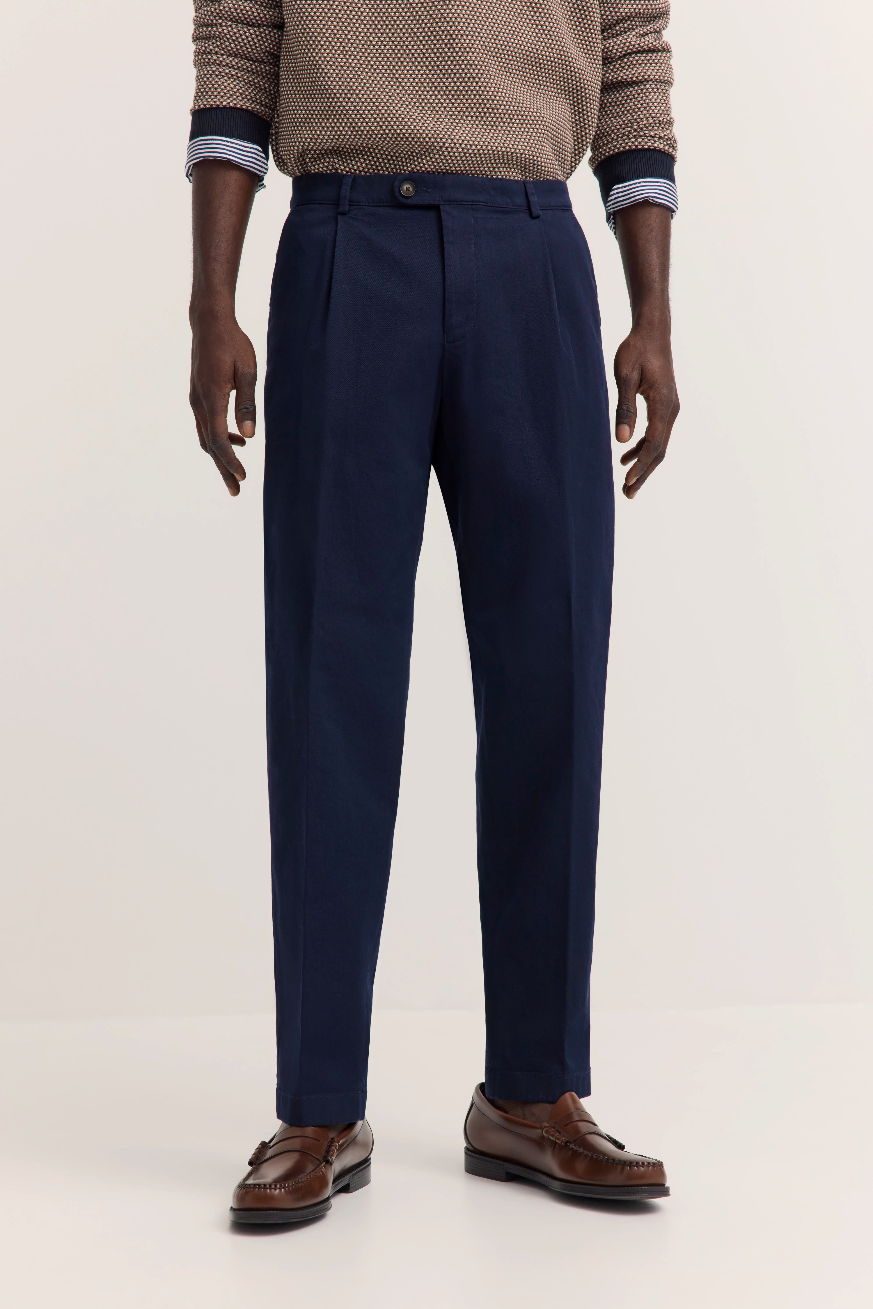 bugatti Model mit braun gemustertem Pullover, blauer Hose und braunen Schuhen, entspannte Pose.