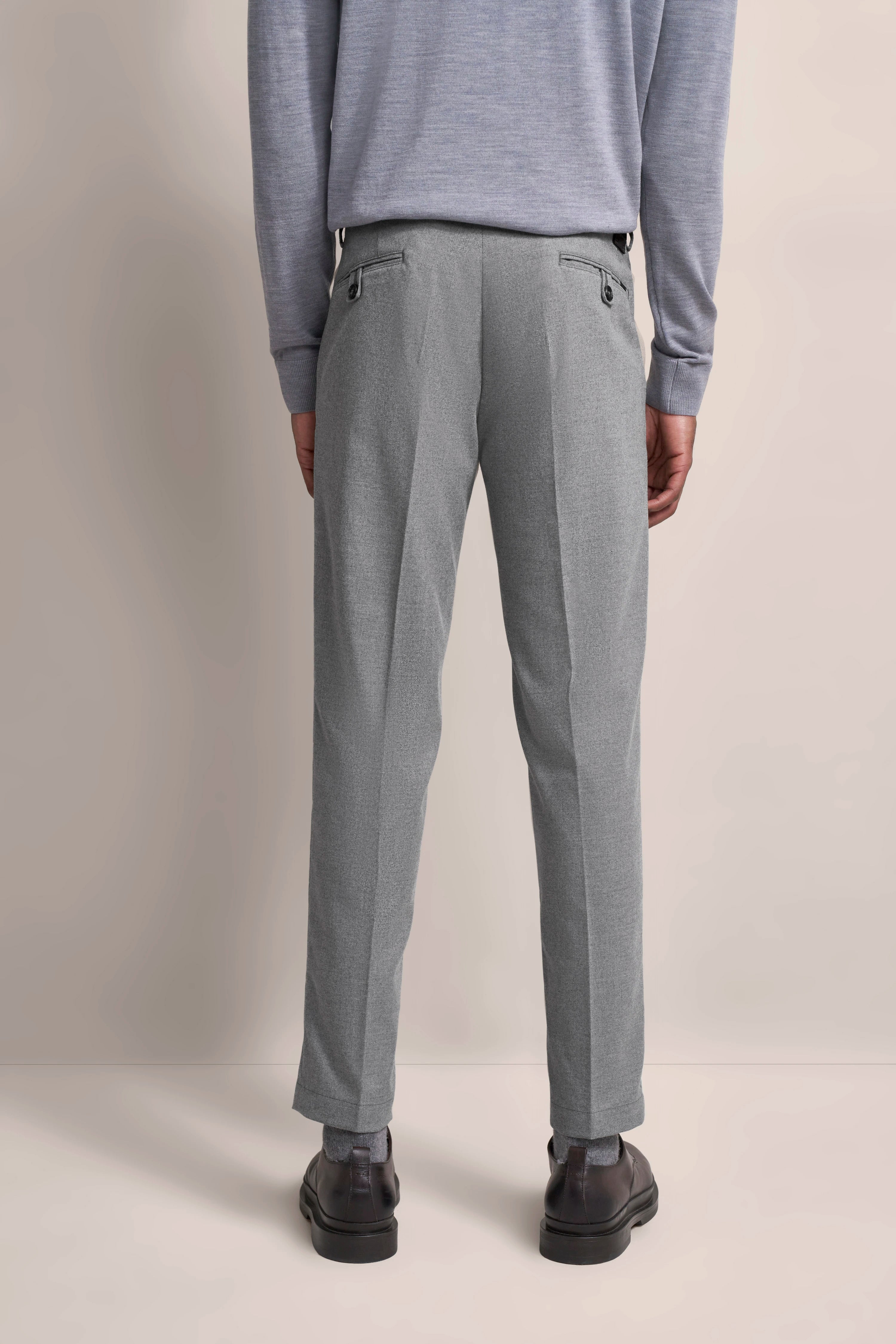 Graue Anzughose, Rückenansicht, legeres Modelbild, kombiniert mit hellgrauem Pullover, klassische Eleganz von bugatti.