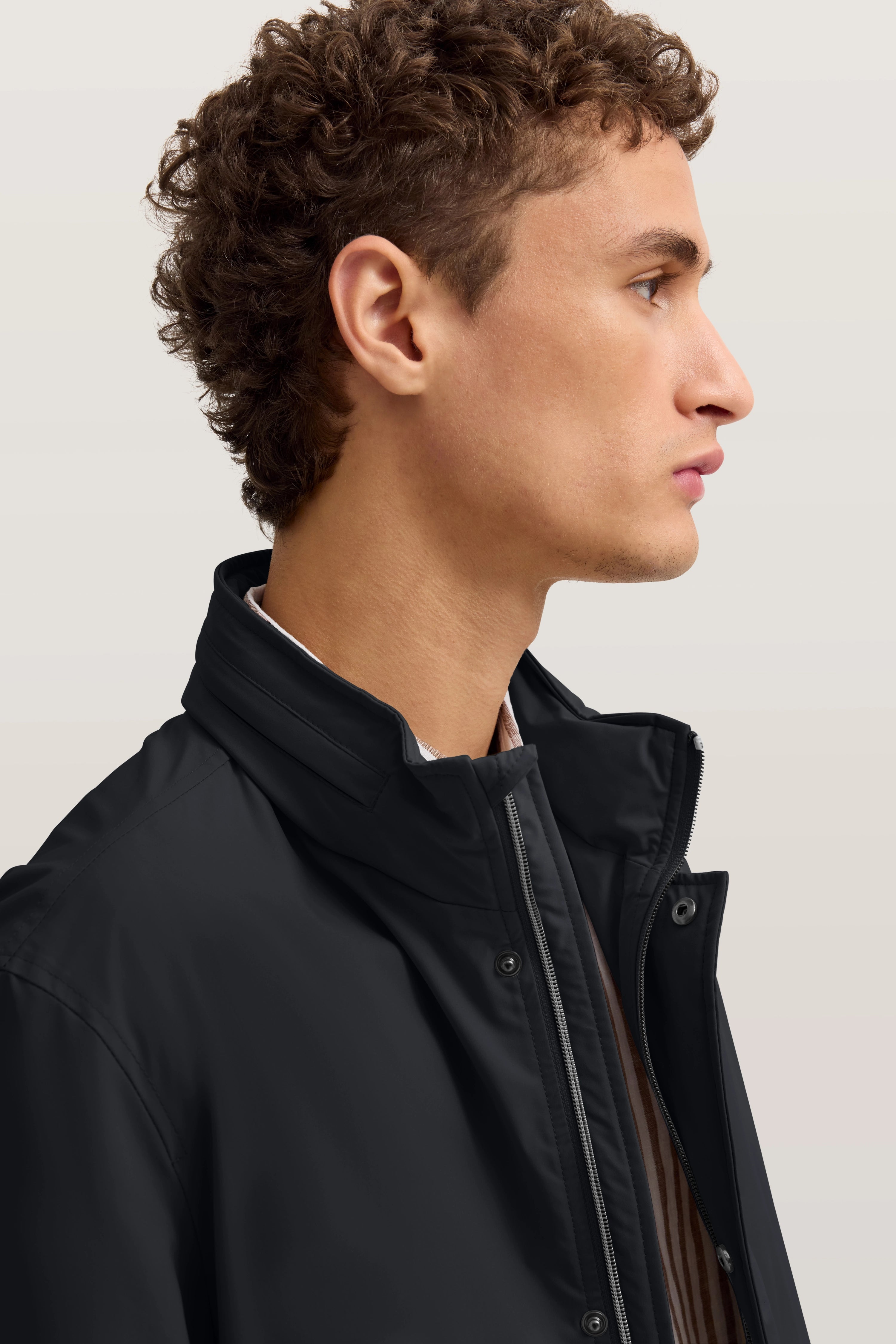 Büstenbild eines Mannes in schwarzer bugatti-Jacke mit Stehkragen, seitliches Profil.