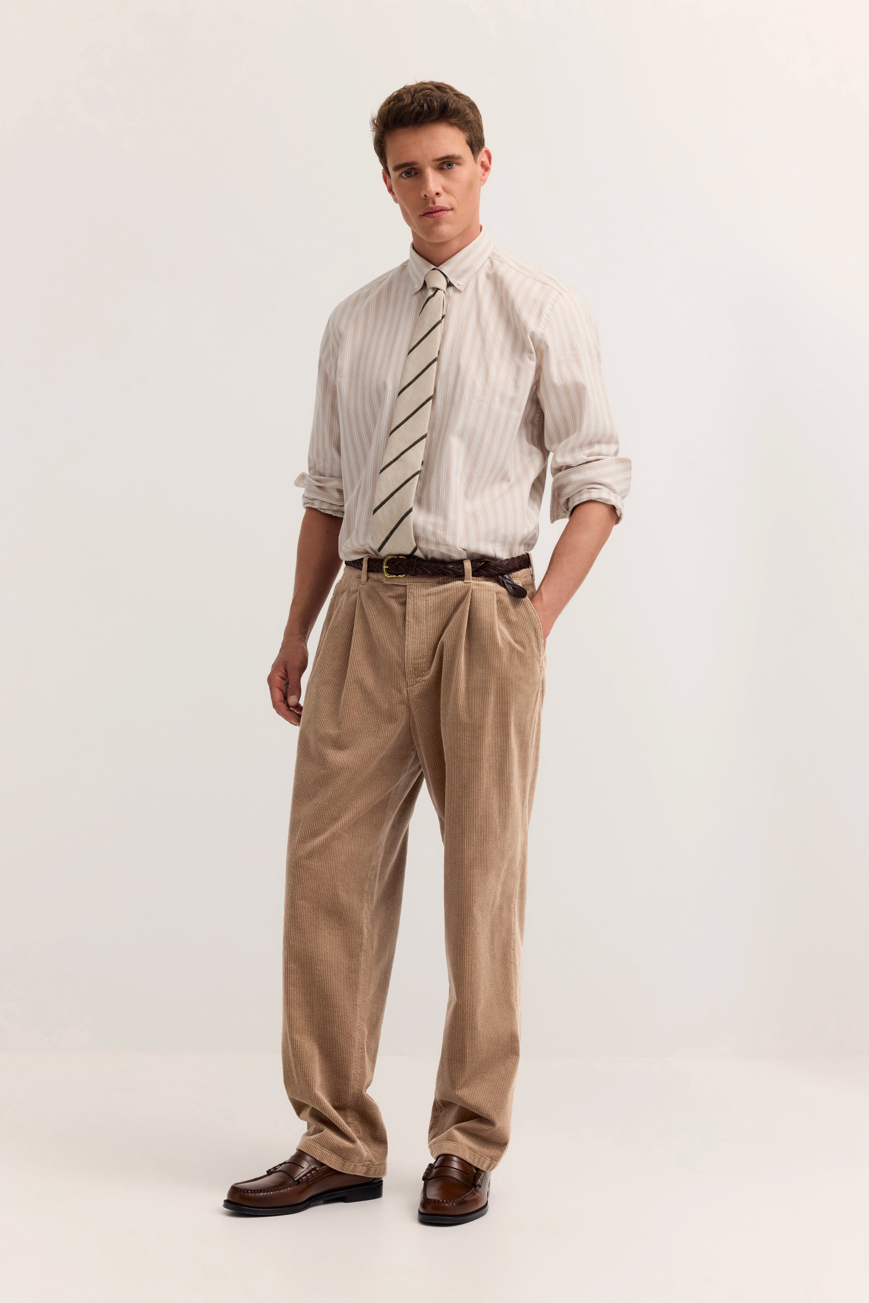 Model in beiger Cordhose, gestreiftem Hemd, Krawatte