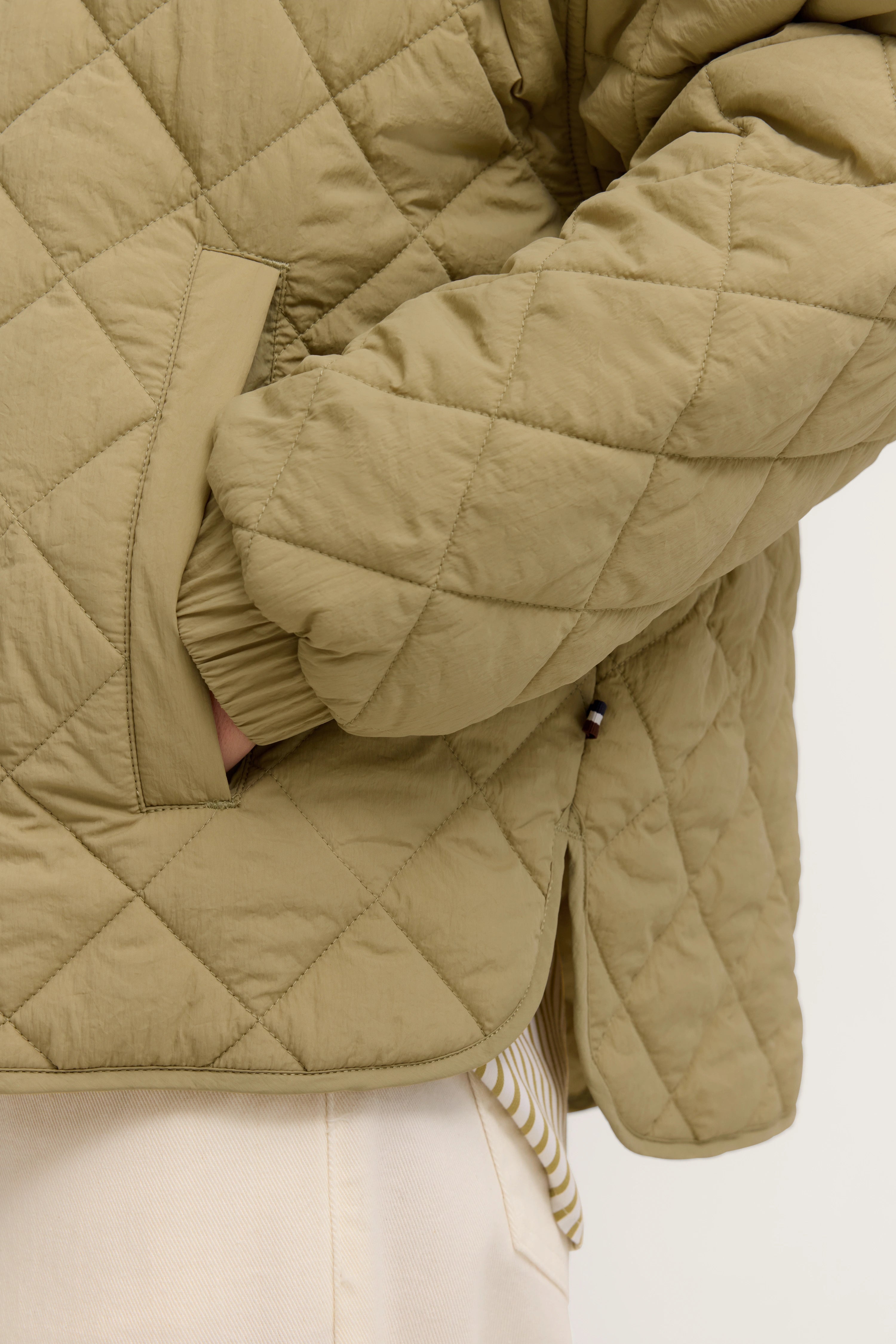 Steppjacke in Beige, Detailansicht, Büstenbild, zeigt Ärmel und Tasche.