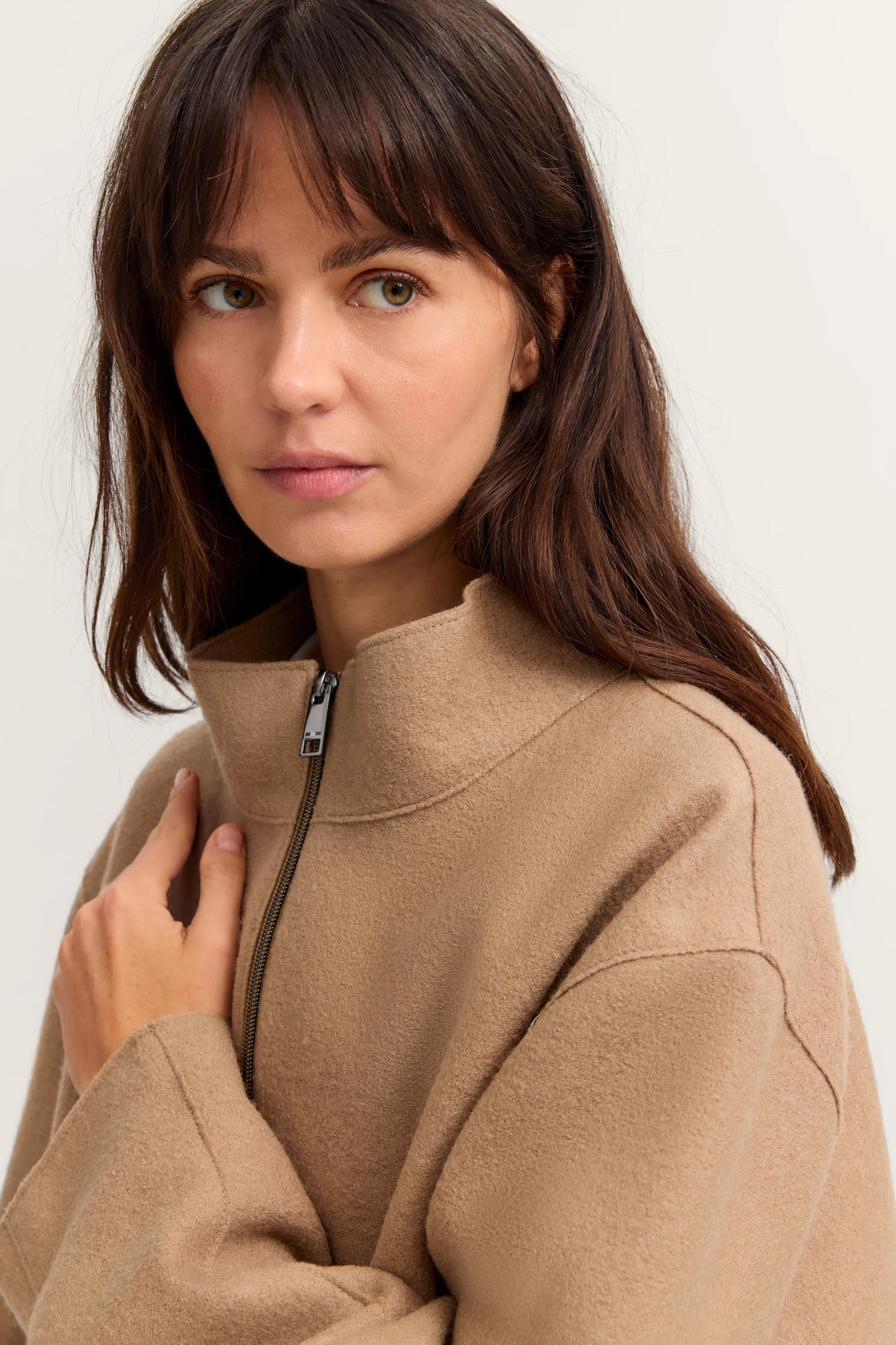 Modelbild mit beigem bugatti Mantel, hochgeschlossener Kragen, lässige Pose, dezent und stilvoll.