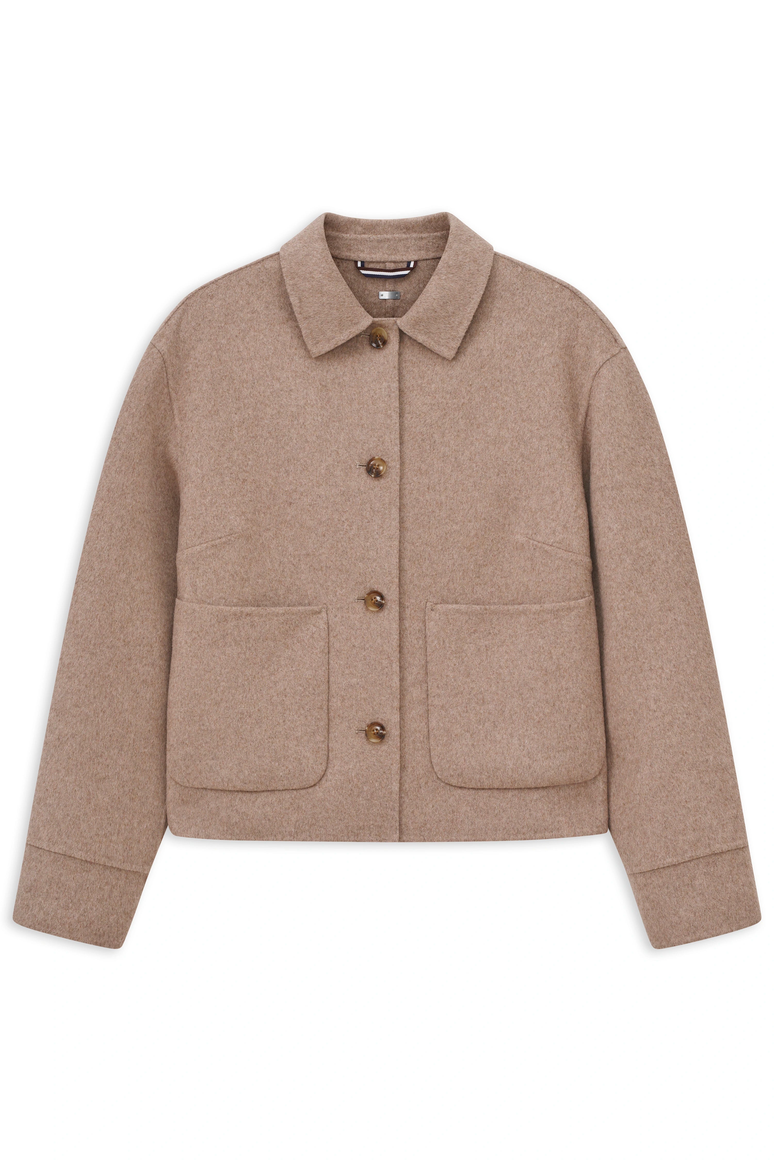 Model trägt beige Jacke, weiße Bluse und beige Hose von bugatti, entspanntes Posing.