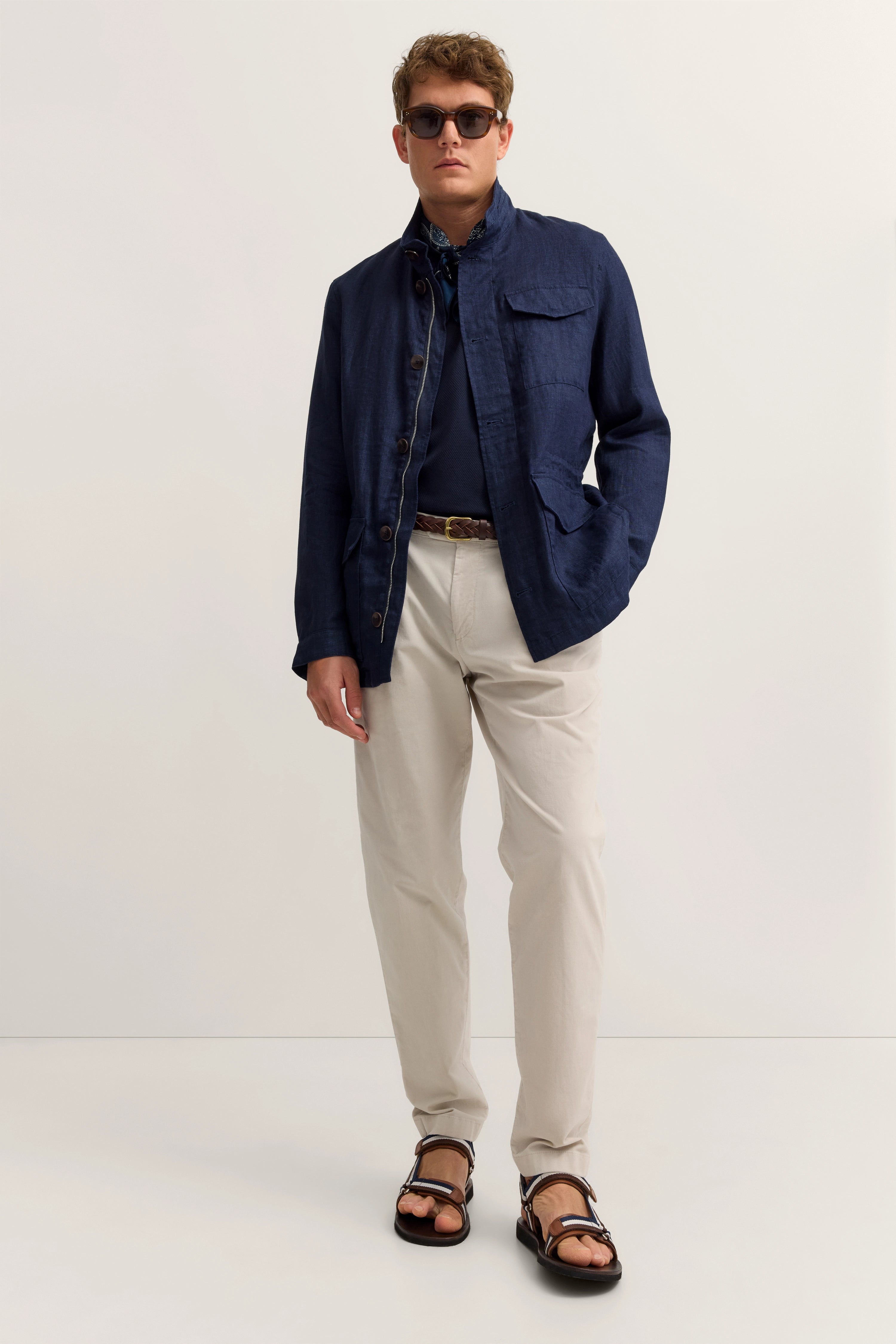 Model in navy Jacke, dunklem Shirt, beige Hose, braunen Sandalen