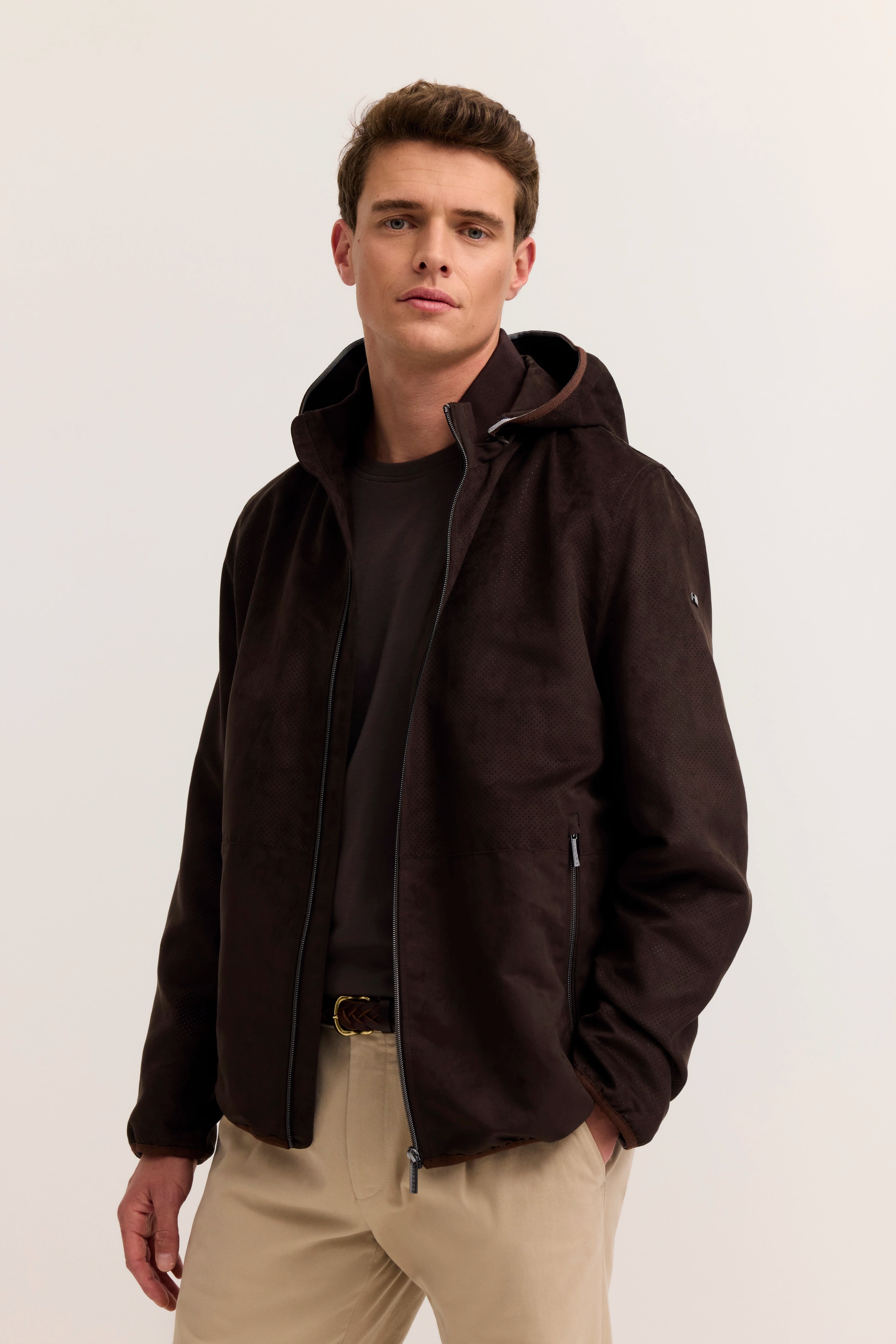 Model trägt braune bugatti Jacke mit Kapuze, schwarzes Shirt, beige Hose