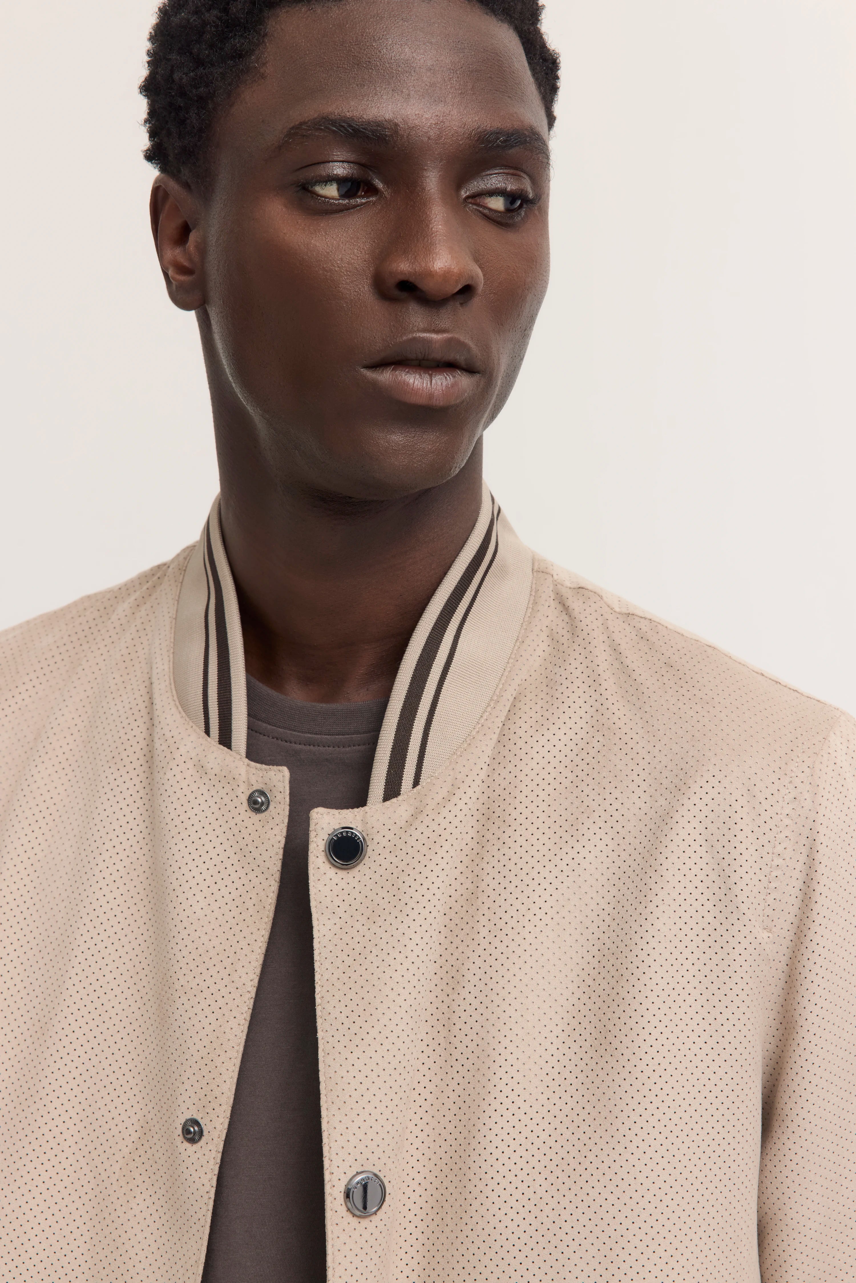 Beiger bugatti Blouson, perforiert, legeres Modelbild, dezente Pose.