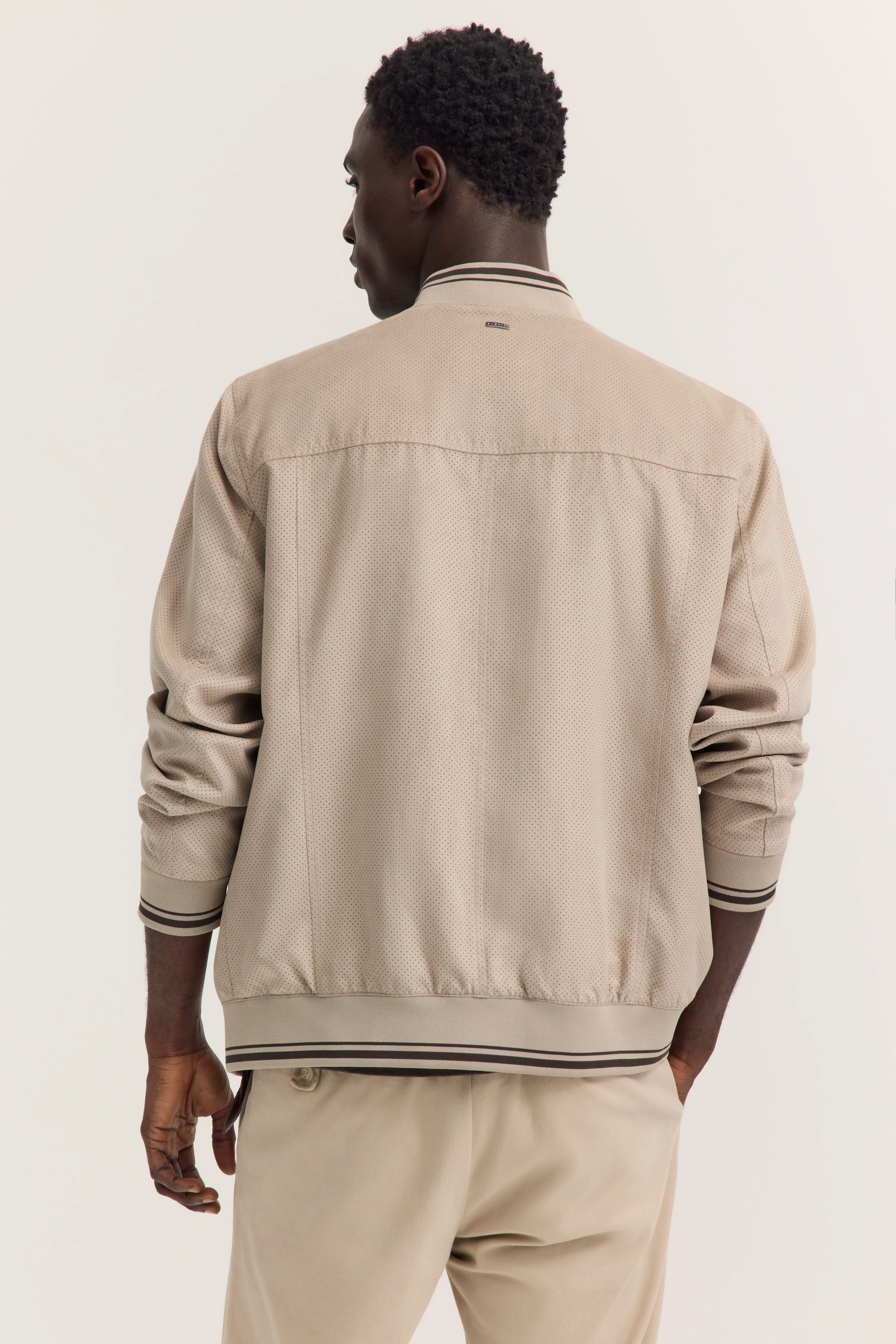 Bugatti Modelbild: Beige Jacke und Hose, Rückansicht, lässiger Stand.