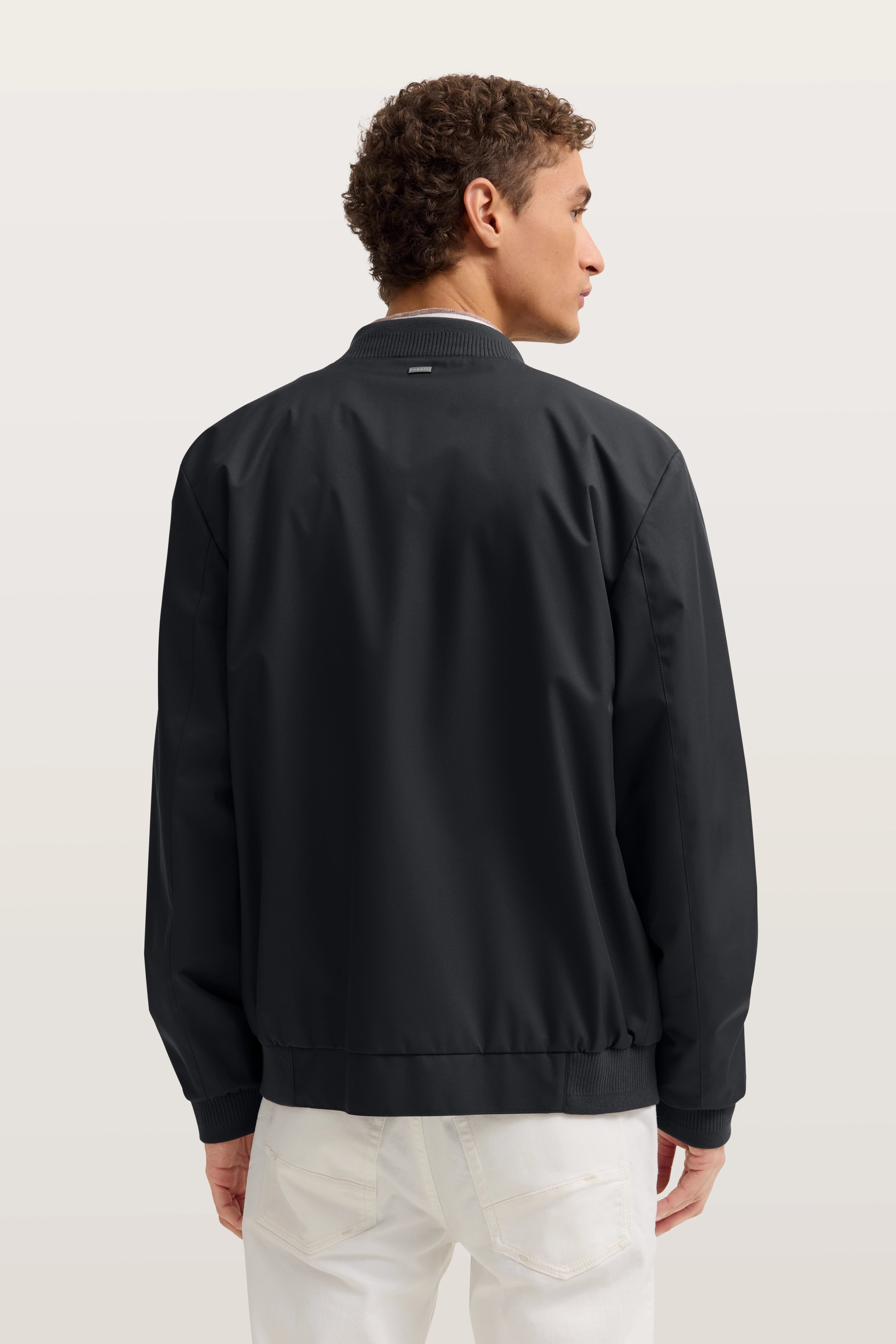 Schwarze bugatti Jacke, Rückansicht auf Model, entspannter Look.