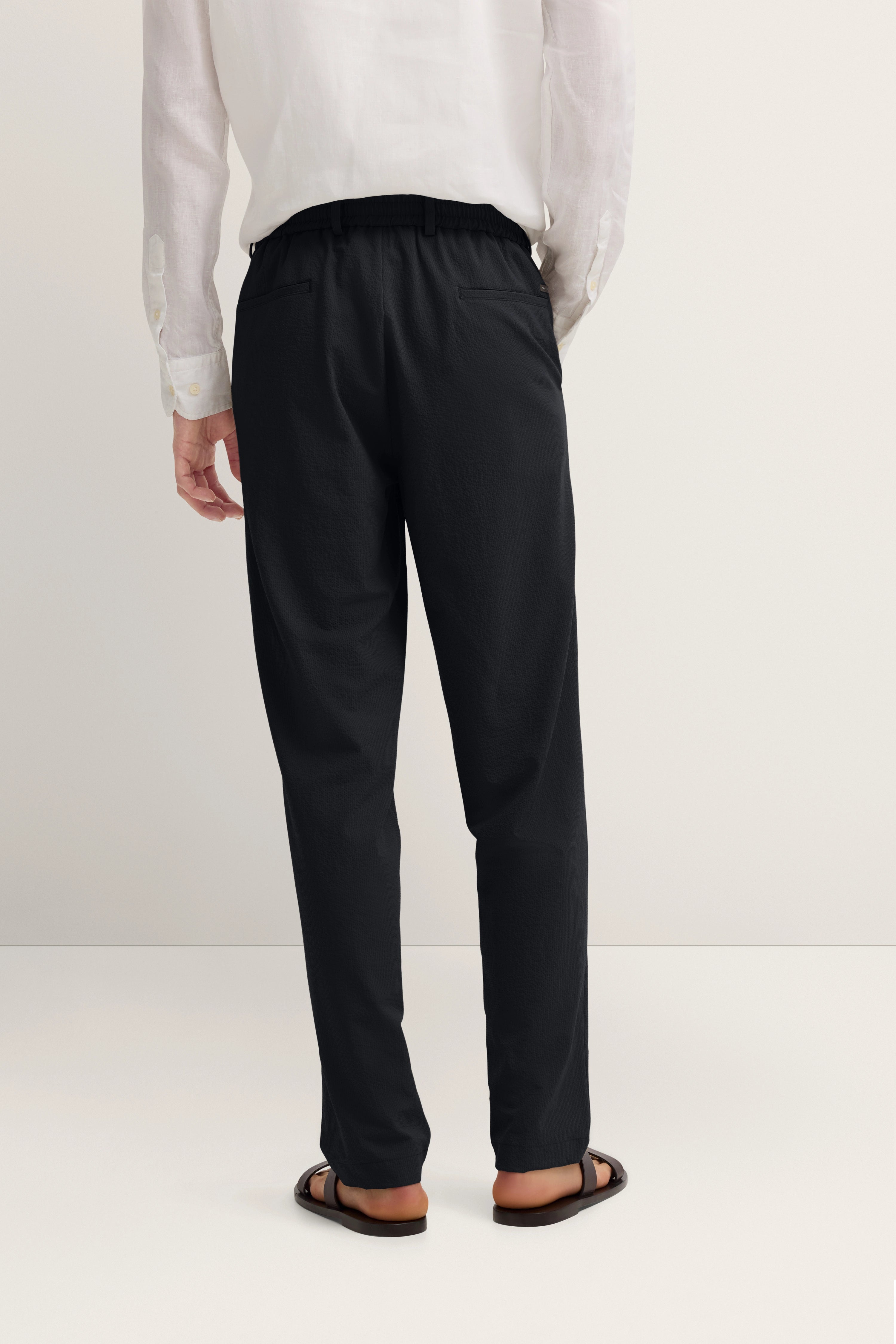 Weißes Hemd und schwarze Hose, legeres Modelbild, Rückenansicht.