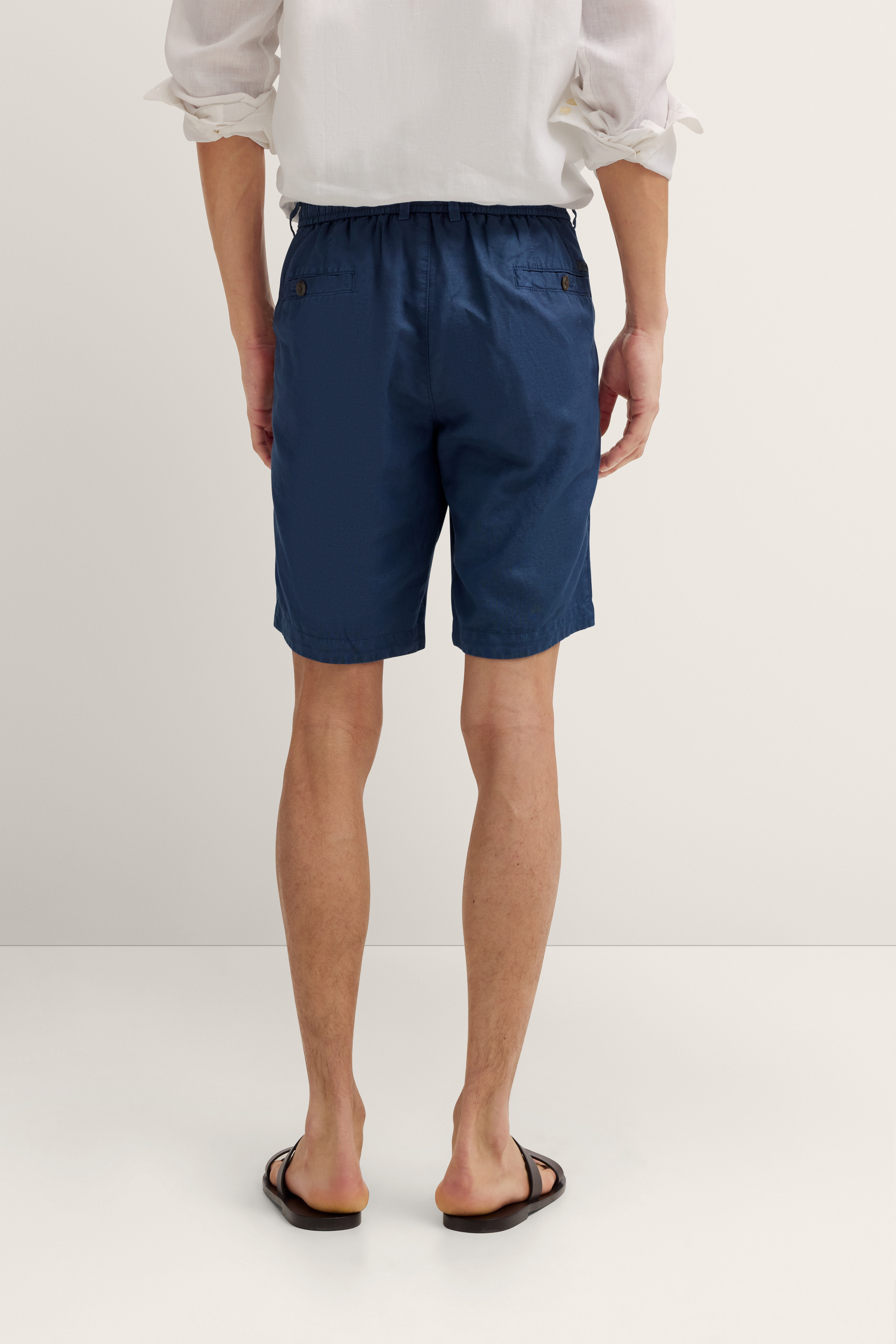 Weißes Hemd und blaue Shorts, Rückansicht, legeres Modelbild.