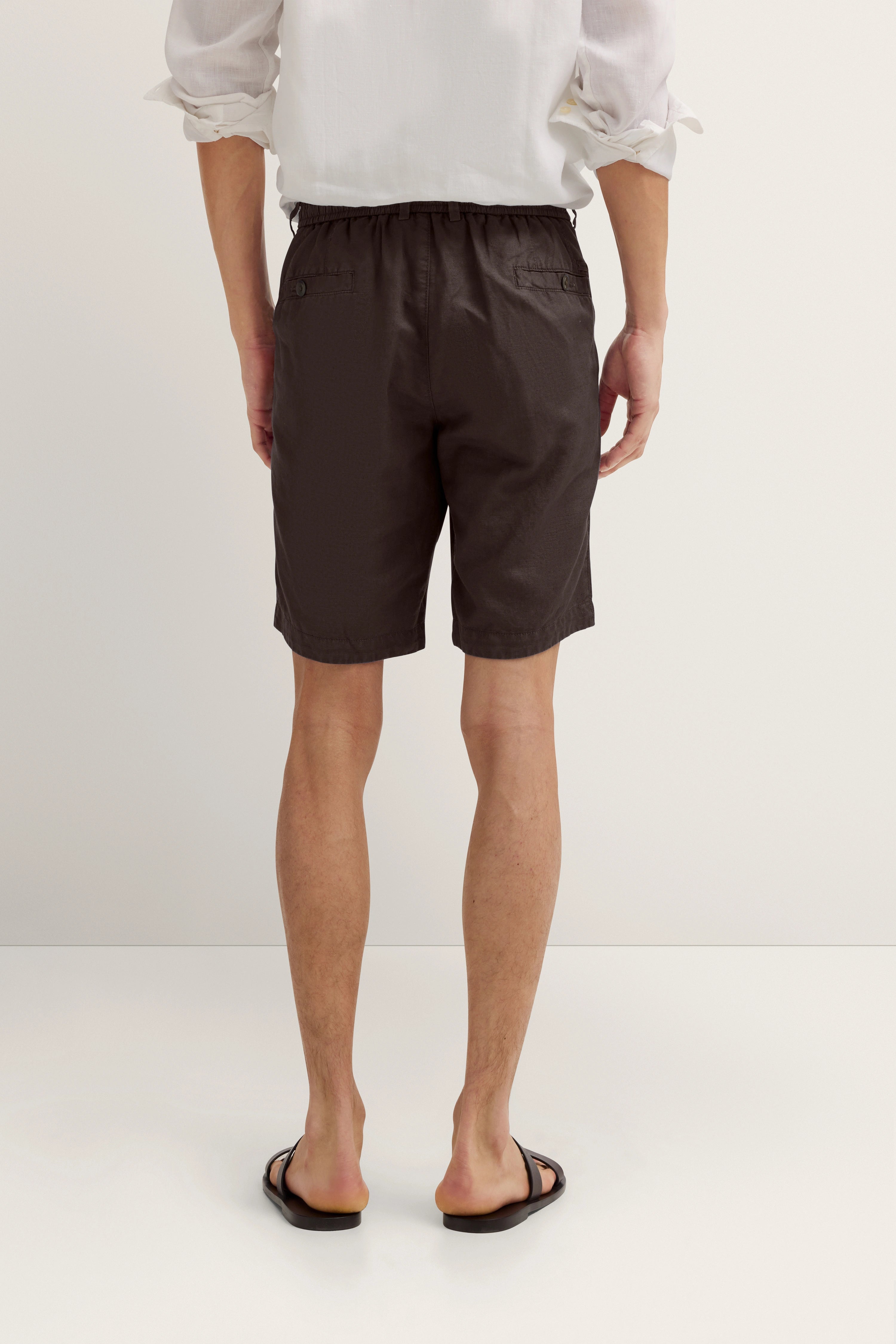 Model in weißem Hemd und dunklen Shorts, Rückansicht, lässiges Outfit von bugatti.
