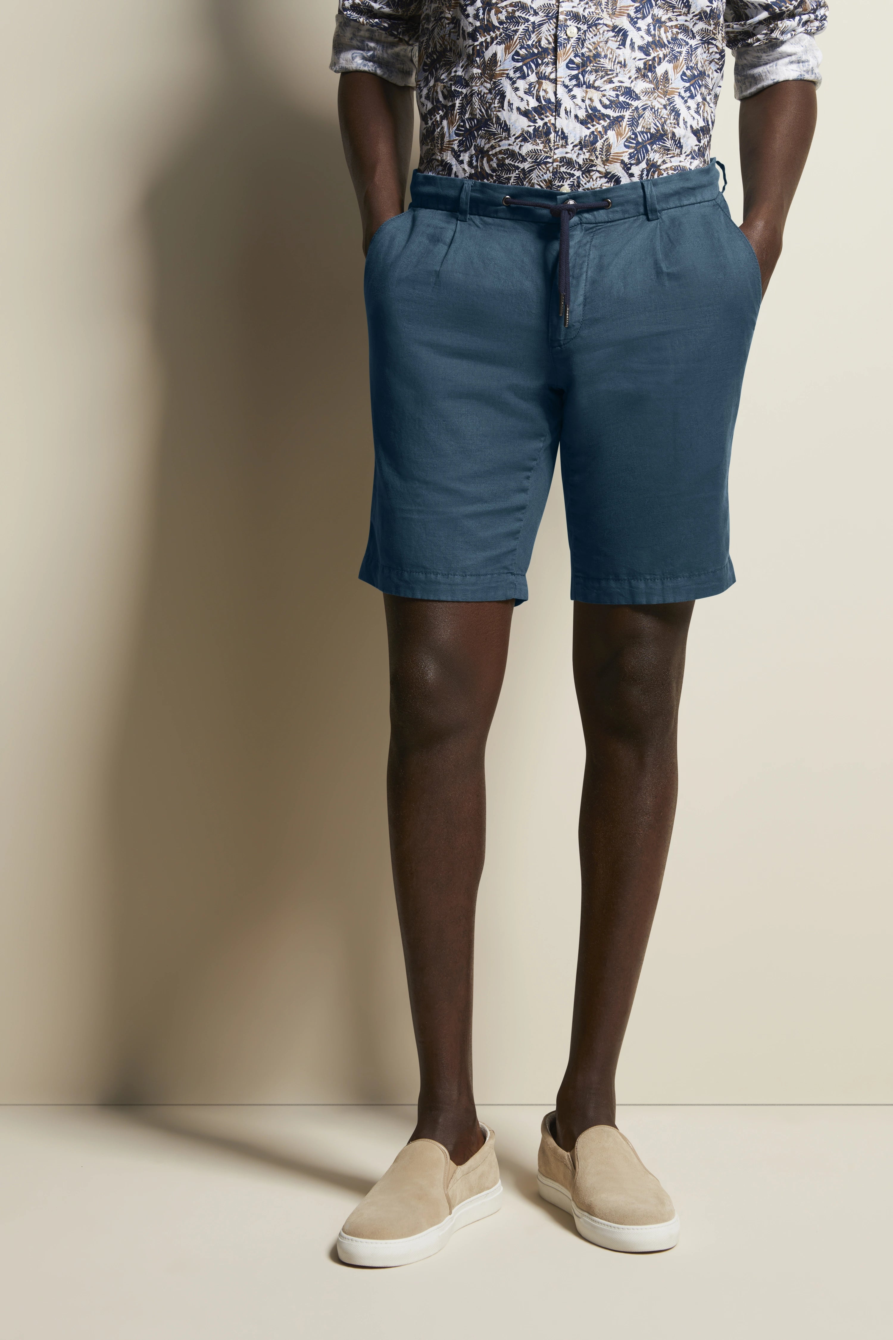 Blau gemusterte Hemd, blaue Shorts, beiges Schuhwerk