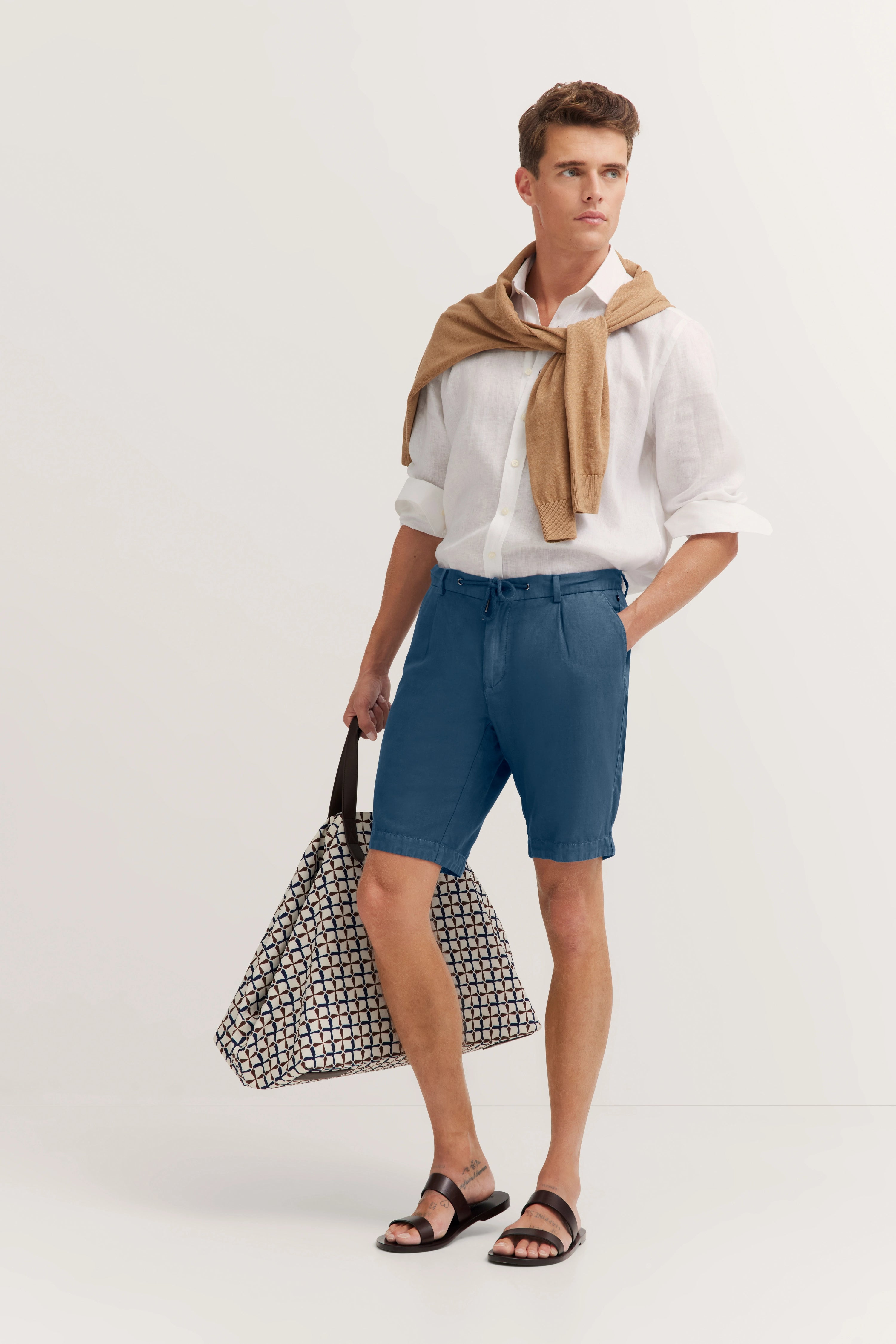 Achteraanzicht van een casual outfit met blauwe shorts en wit overhemd, gedragen door een model.