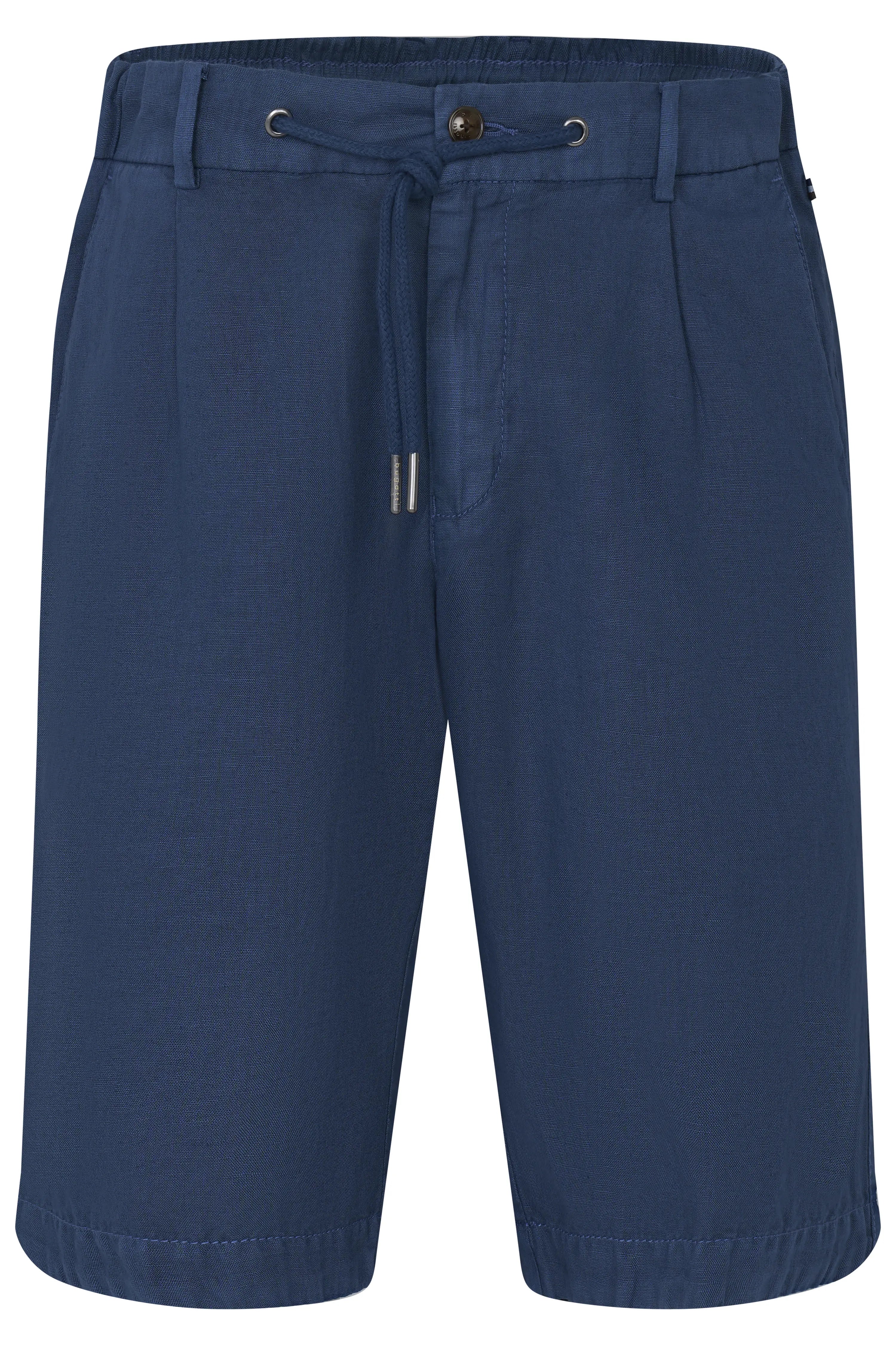 Model in wit hemd, blauwe shorts, beige trui over schouders, gemêleerde tas, zwarte sandalen.