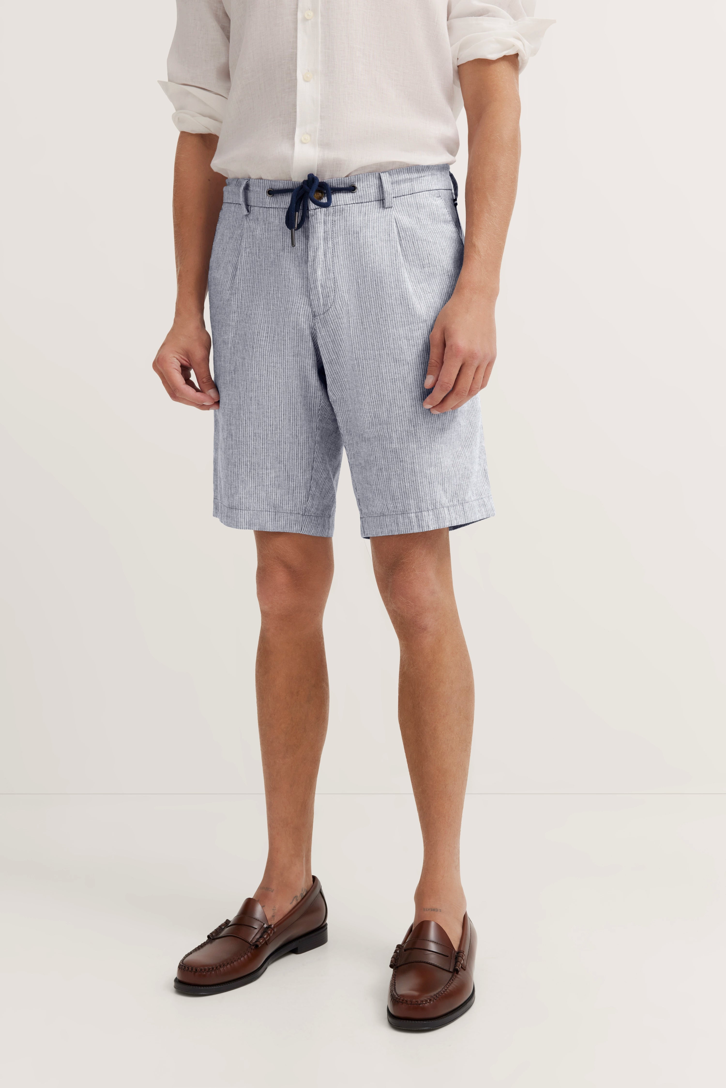 Legerbild: Weißes Hemd, hellblaue Shorts, braune Loafer von bugatti.