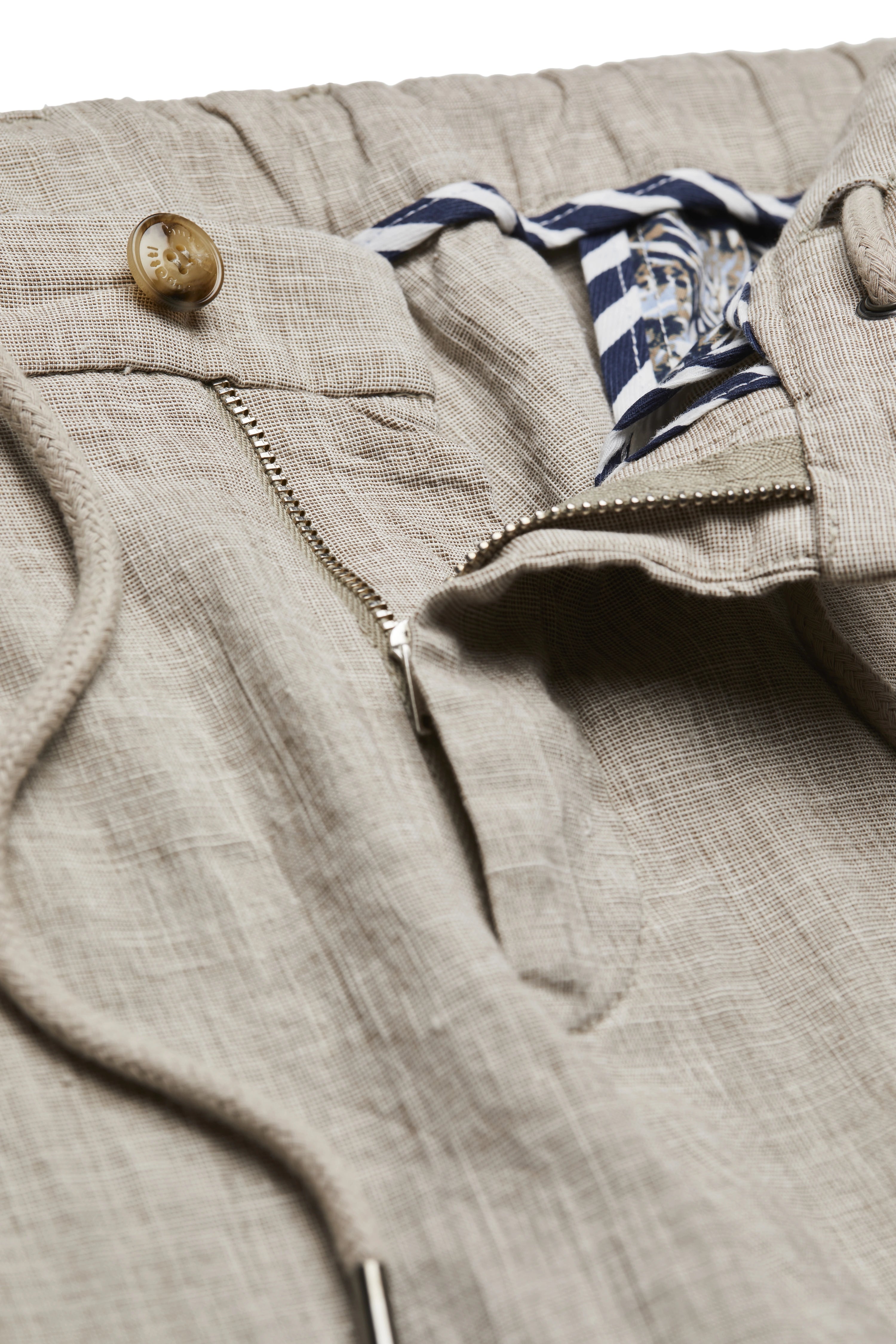 Beige bugatti broek met streepdetail, close-up van textuur en vetersluiting.