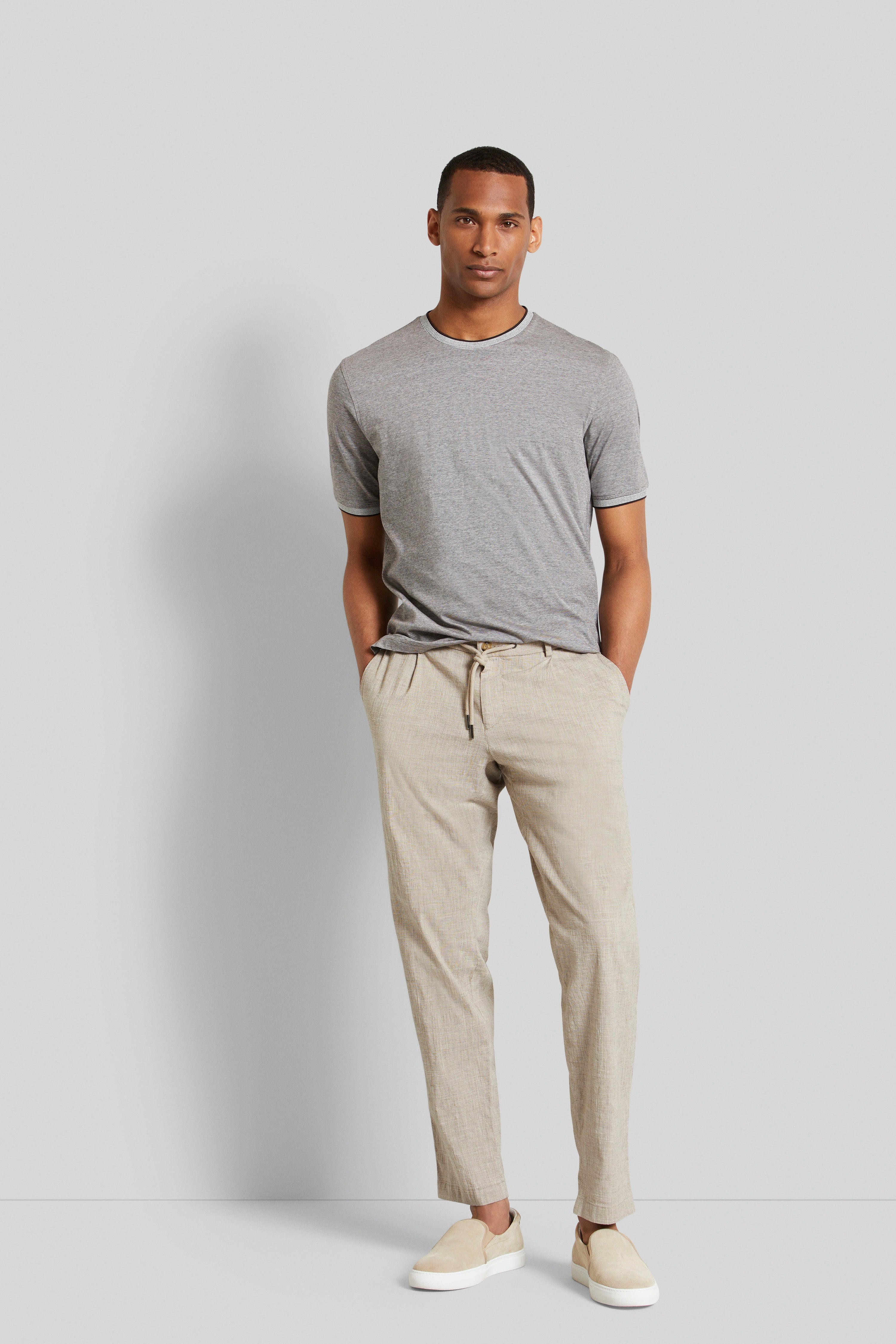 Graues T-Shirt, beige Hose, leger, Model steht entspannt, bugatti Outfit.