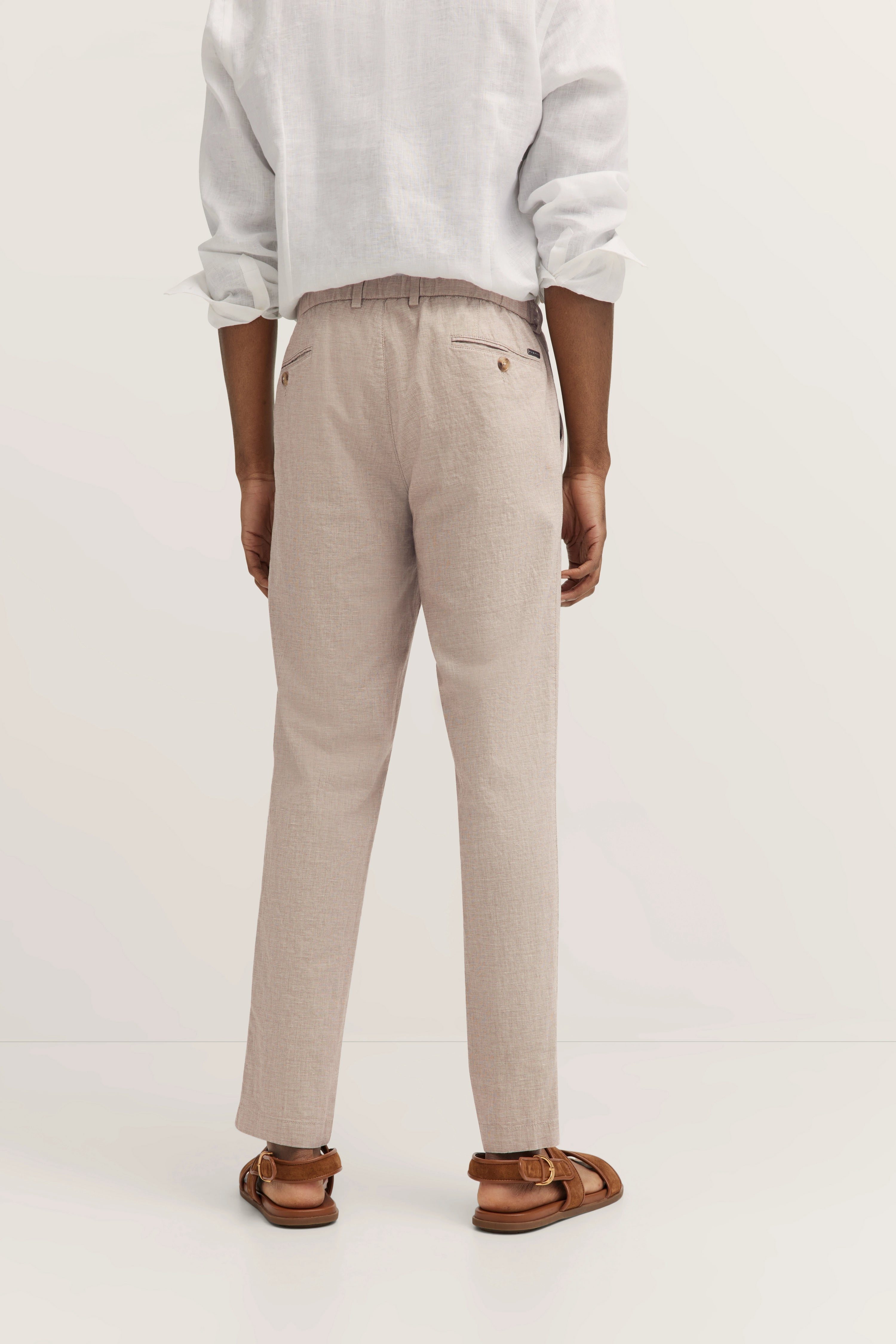 Model in lässigem Outfit, weißes Hemd, beige Hose. Rückansicht. Ideal für eleganten Casual-Look.