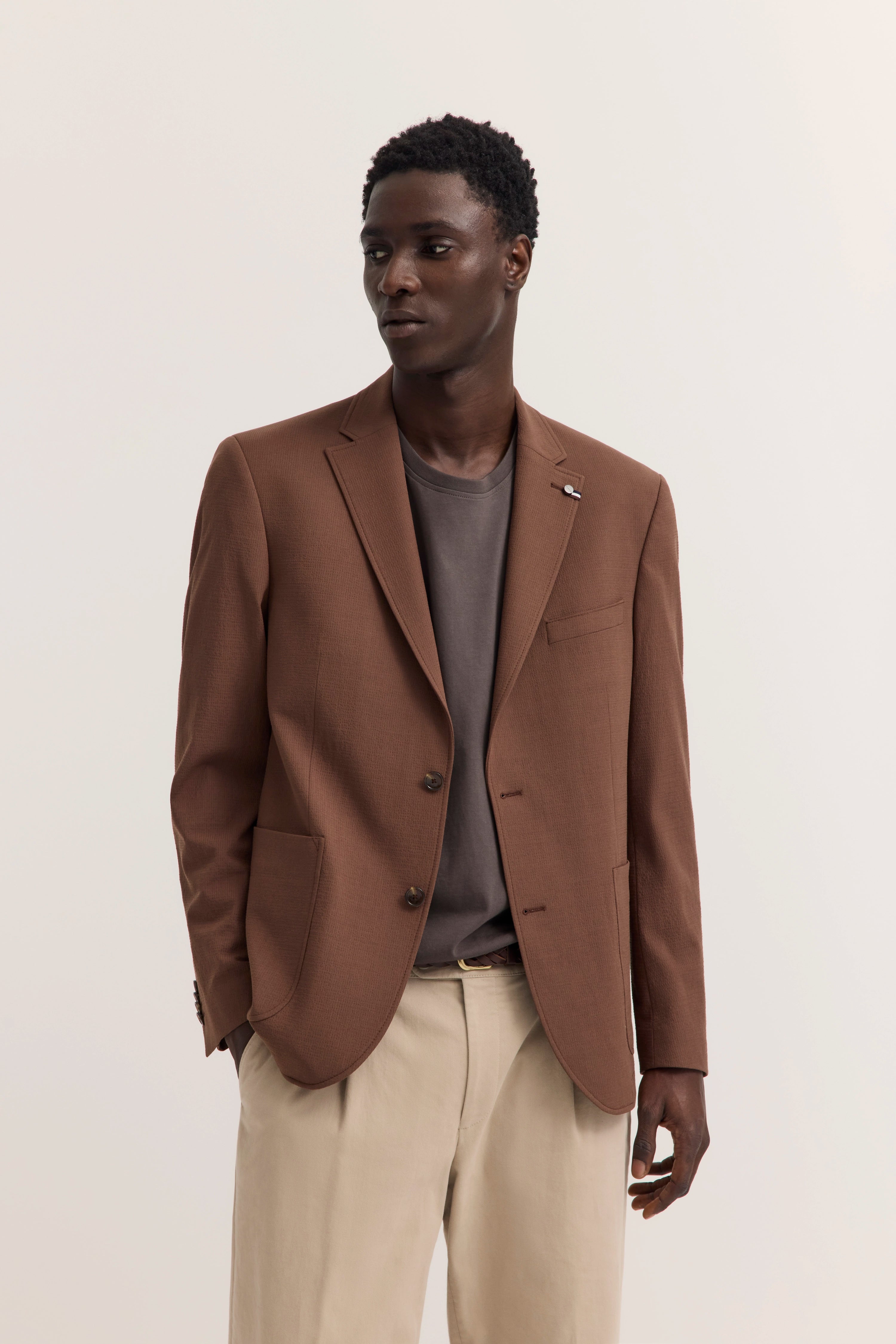 Brauner bugatti Blazer mit grauem Shirt und beigen Hosen, Modelbild, entspannte Pose.