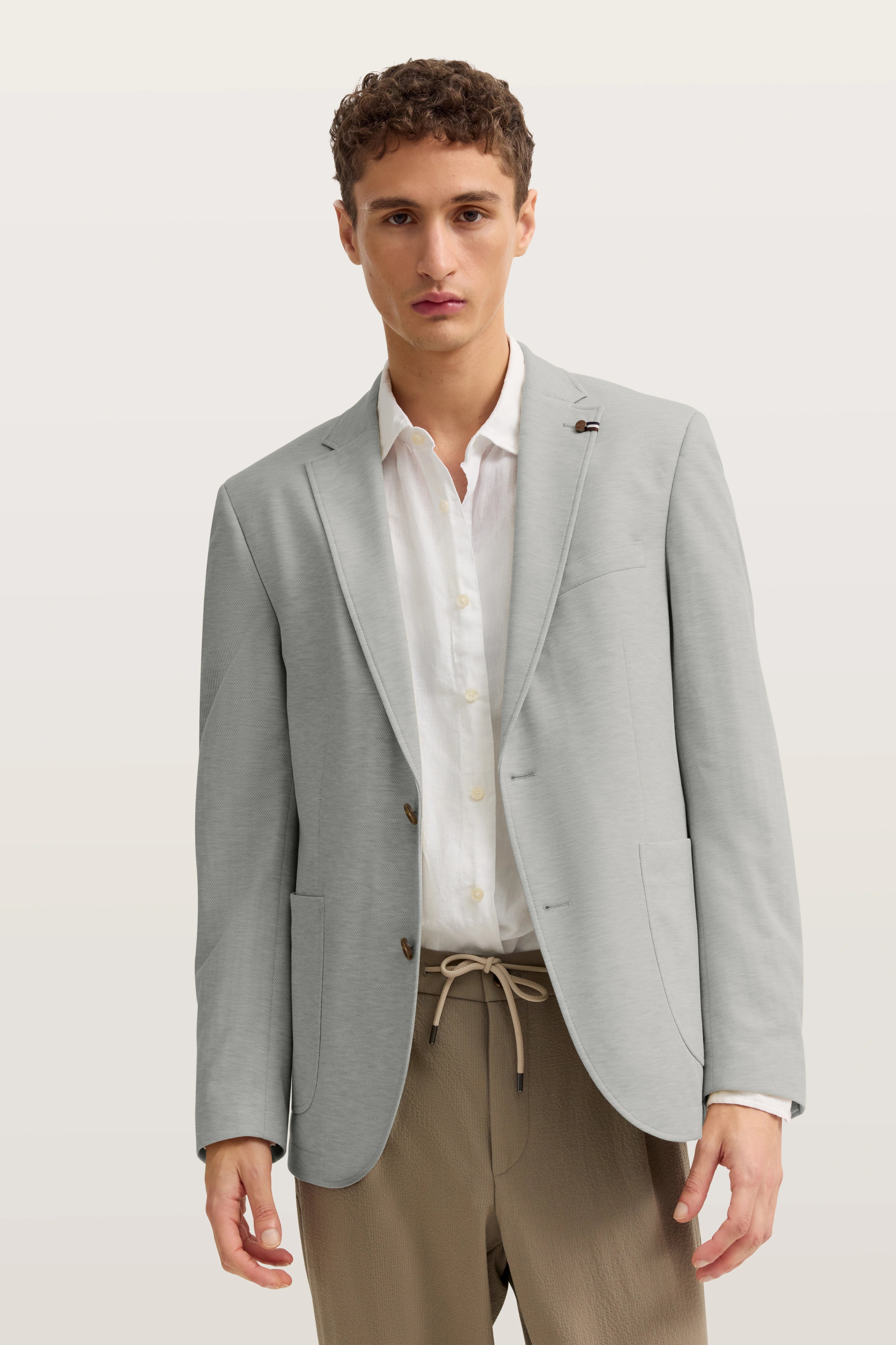 Model trägt grauen bugatti Blazer, weiße Hemd, beige Hose