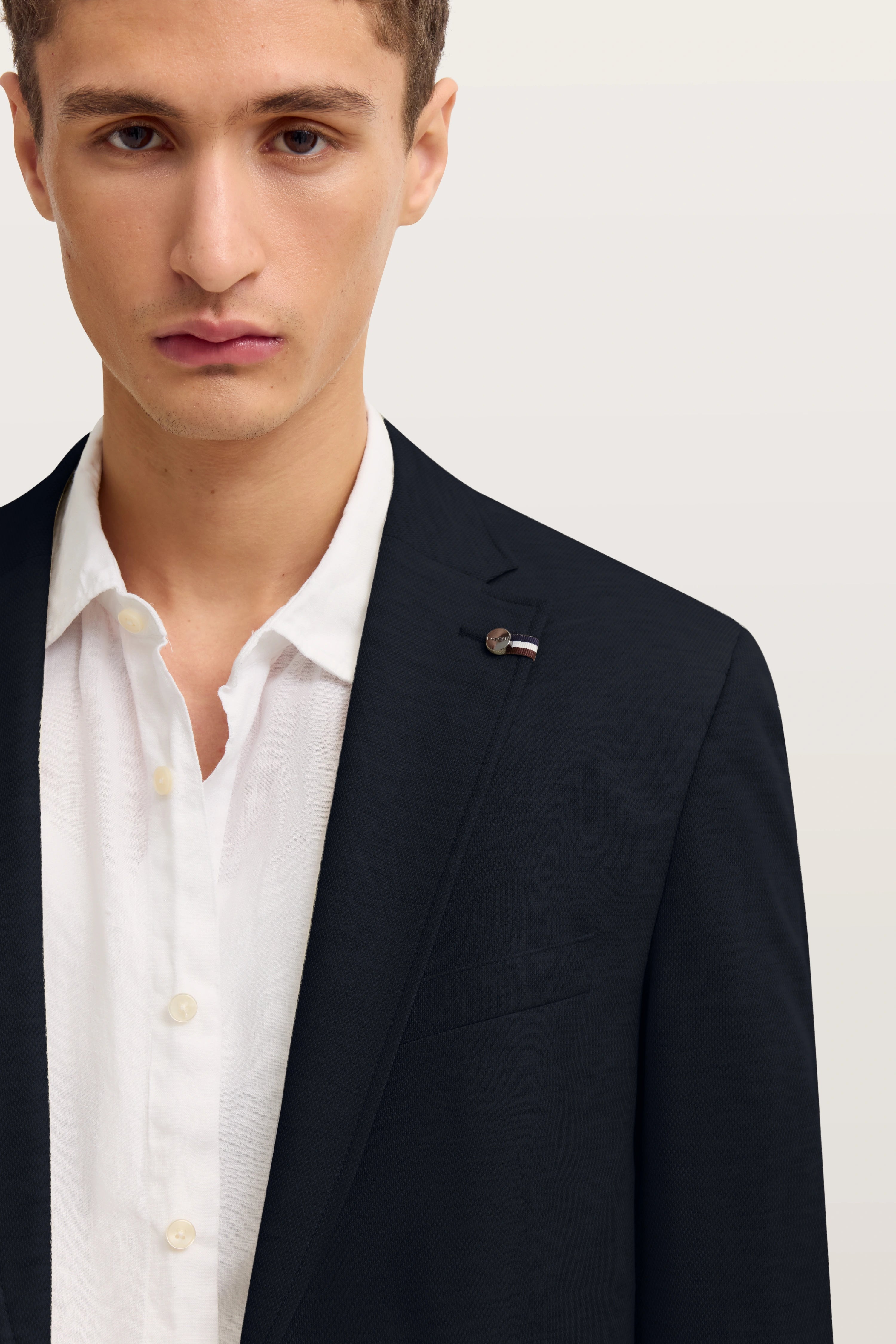 bugatti Modelbild: Weißes Hemd, schwarzes Sakko, Halbprofil, eleganter Look.