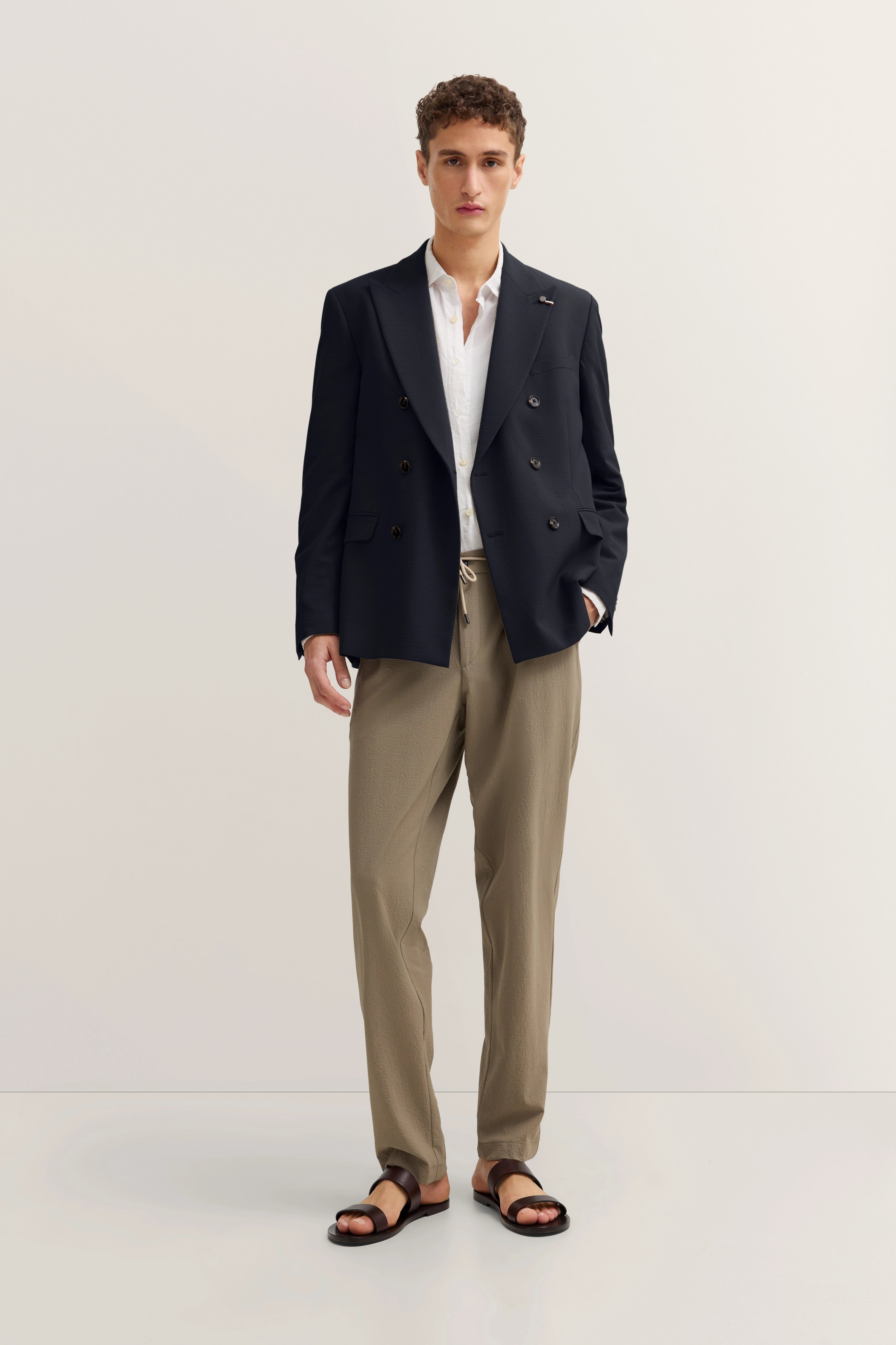 Model in bugatti Blazer, weißem Hemd, beigen Hosen, schwarzen Sandalen