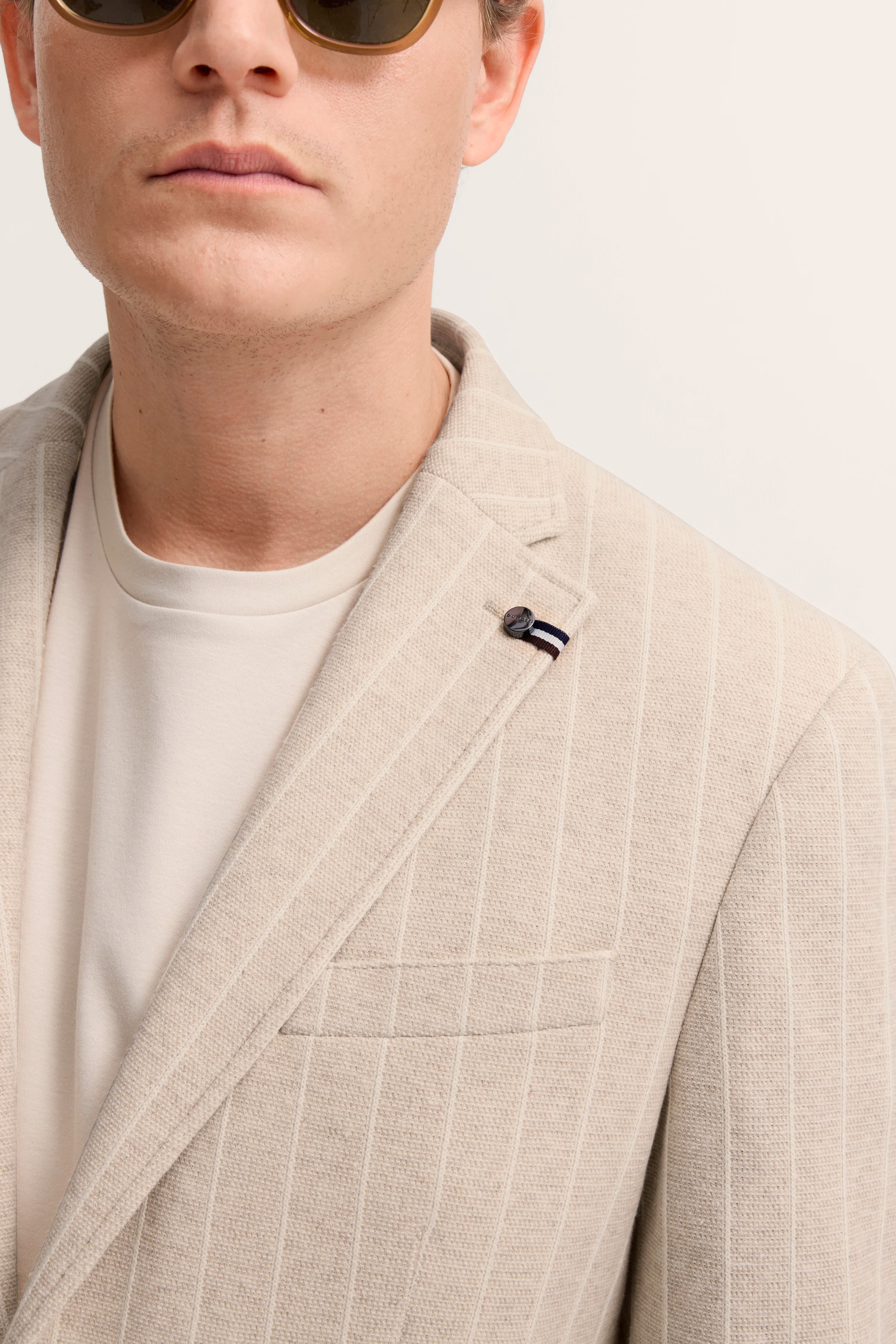 Beiger bugatti Blazer mit feinen Streifen, getragen über einem weißen Shirt, Close-up Büstenbild.