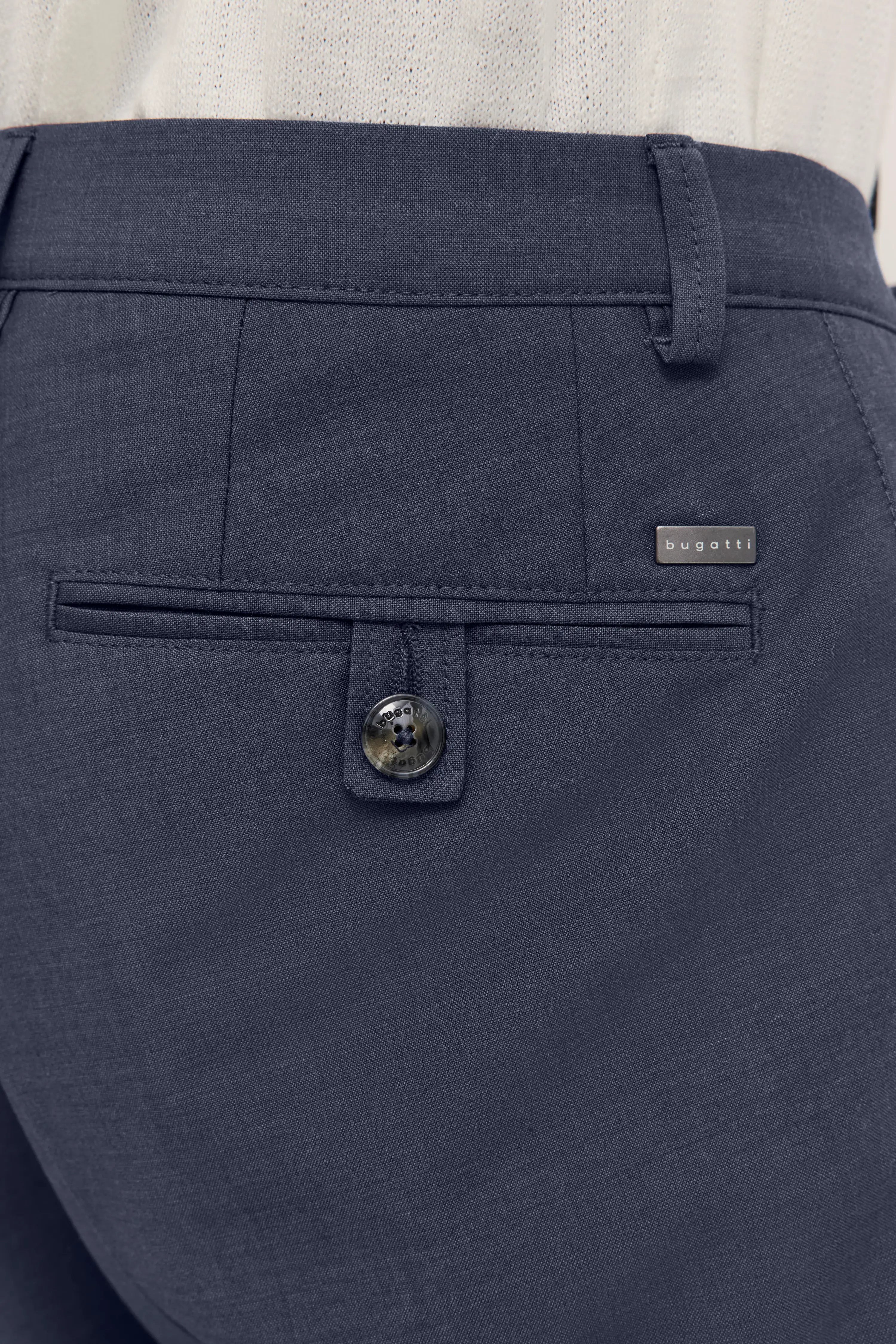 Büstenbild einer dunkelblauen bugatti-Hose mit Knopfdetail und Logo.