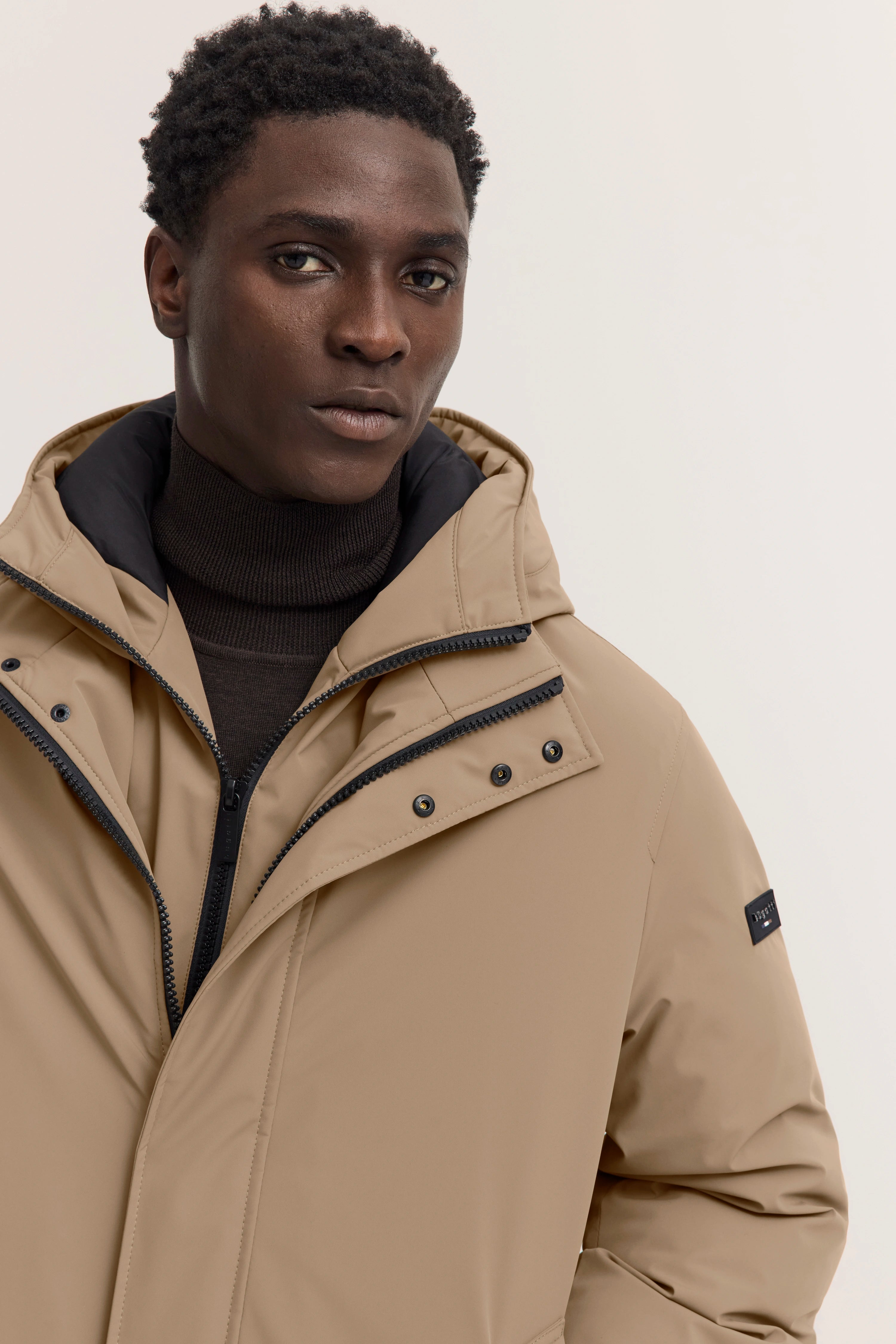 Beigefarbene Jacke von bugatti, getragen von Model, schwarzer Rollkragen.