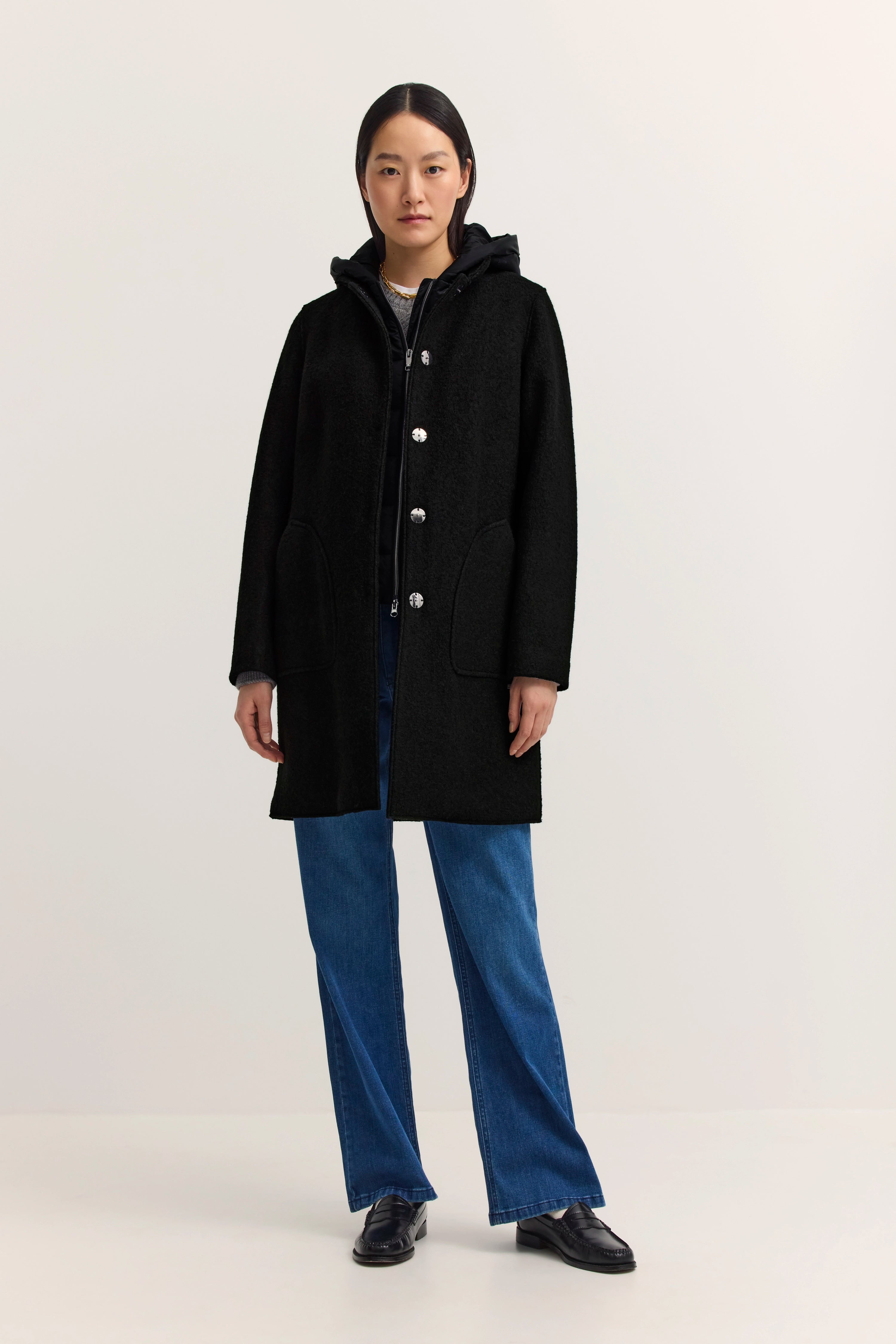 Schwarzer bugatti Mantel, blaue Jeans, legeres Modelbild, entspannte Pose.