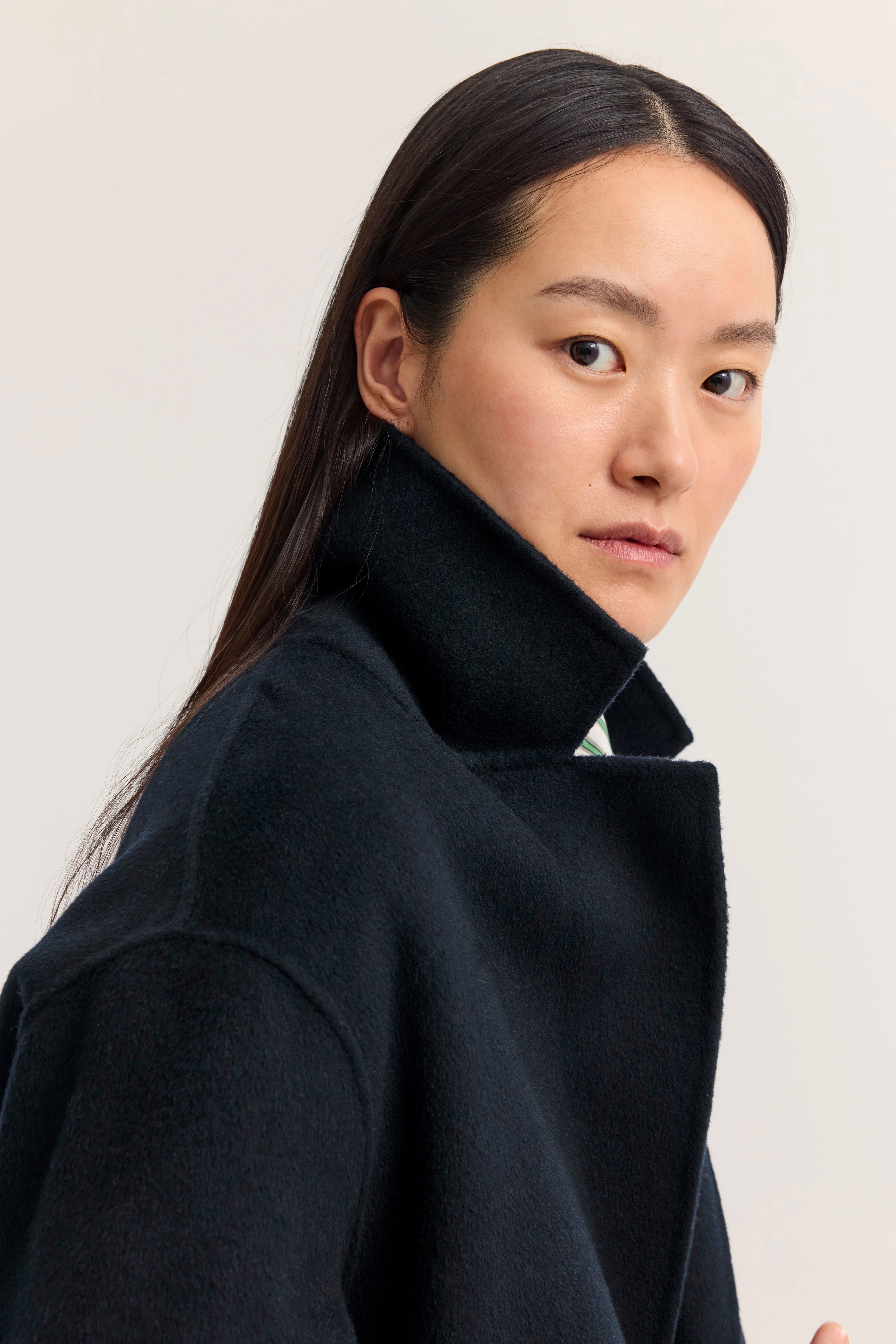 Büstenbild eines Models mit schwarzem bugatti Mantel, eleganter minimalistischer Stil.