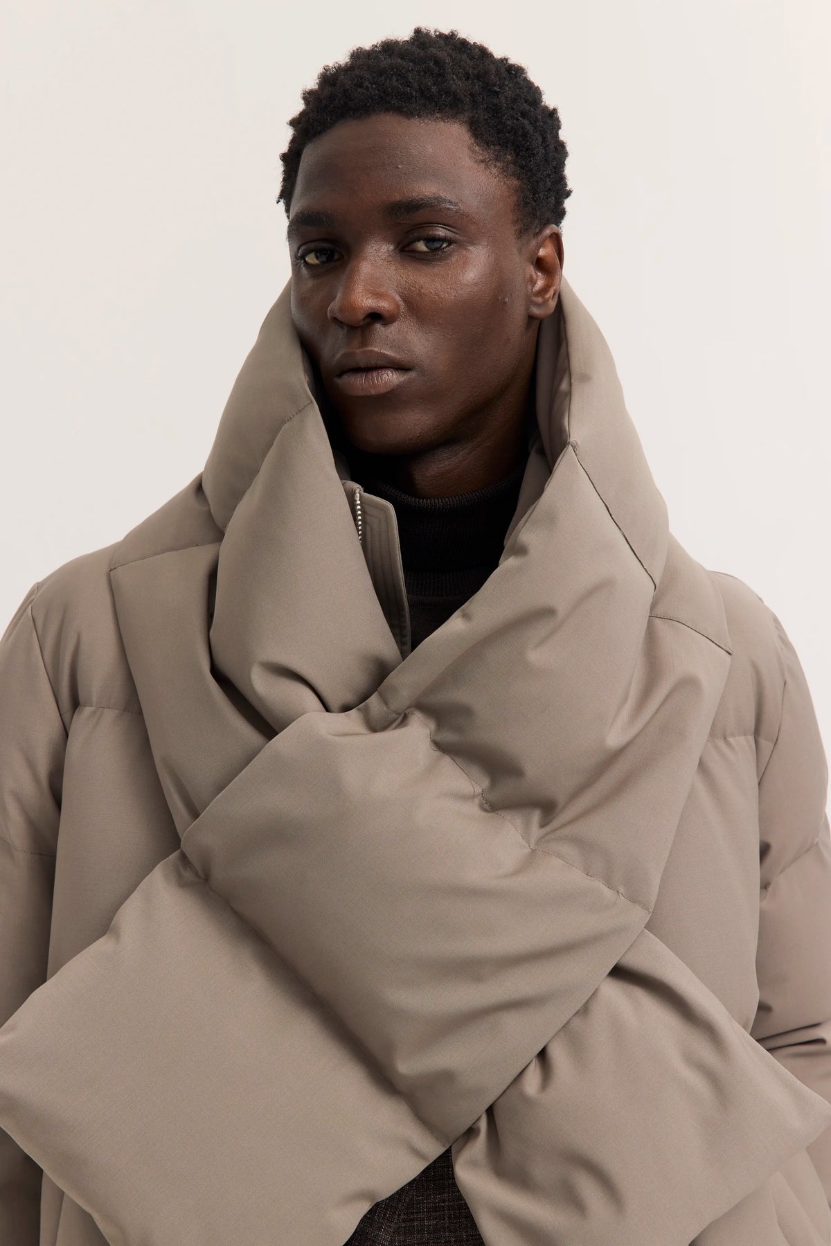 Modelbild: Elegante, beigefarbene Steppjacke von bugatti, locker um den Hals drapiert.