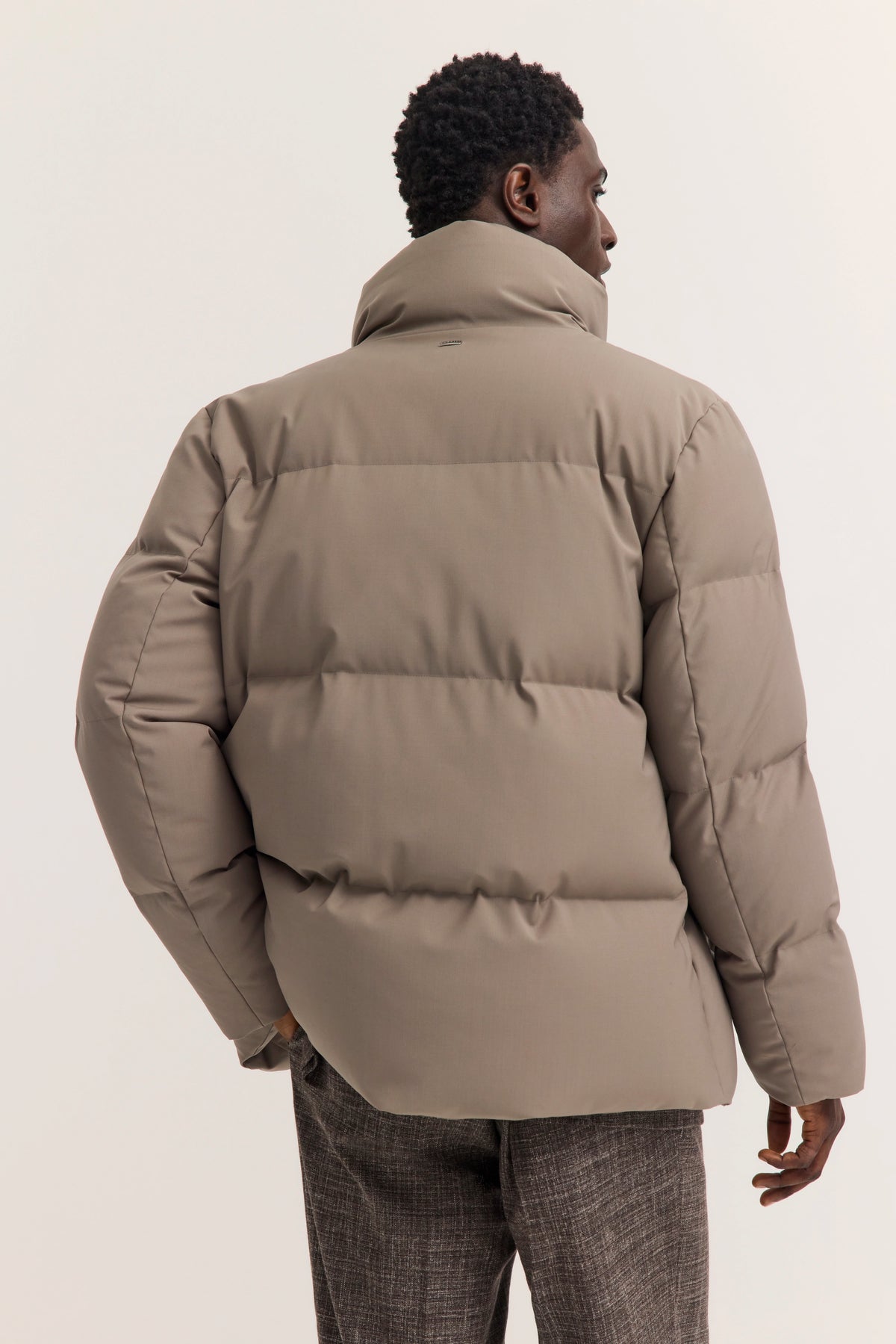 Pufferjacke in Beige von bugatti, Modelbild von hinten, lässige Pose, graue Hose.