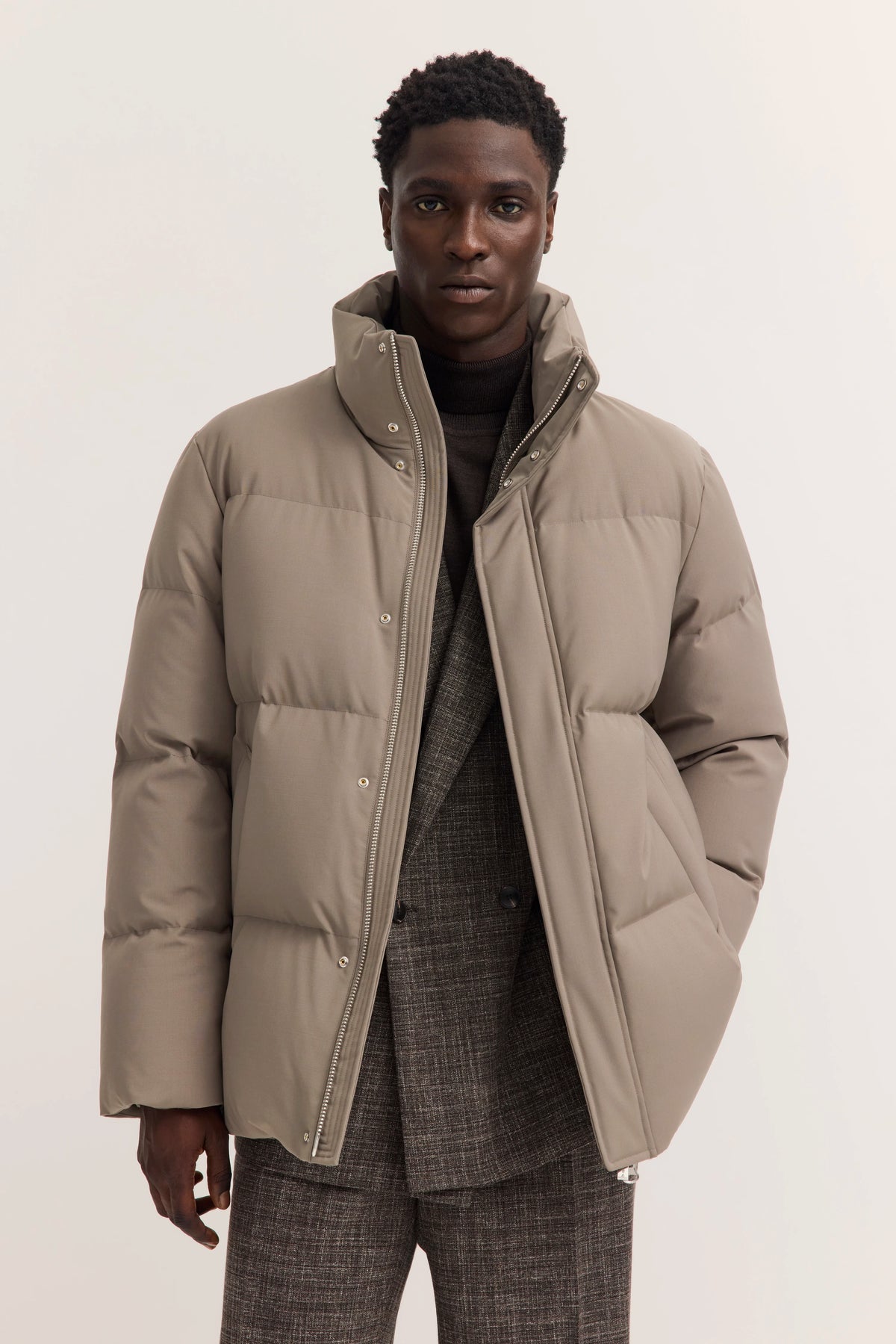 Graue Daunenjacke über kariertem Anzug, Modelbild, frontales Posing, bugatti Stil.