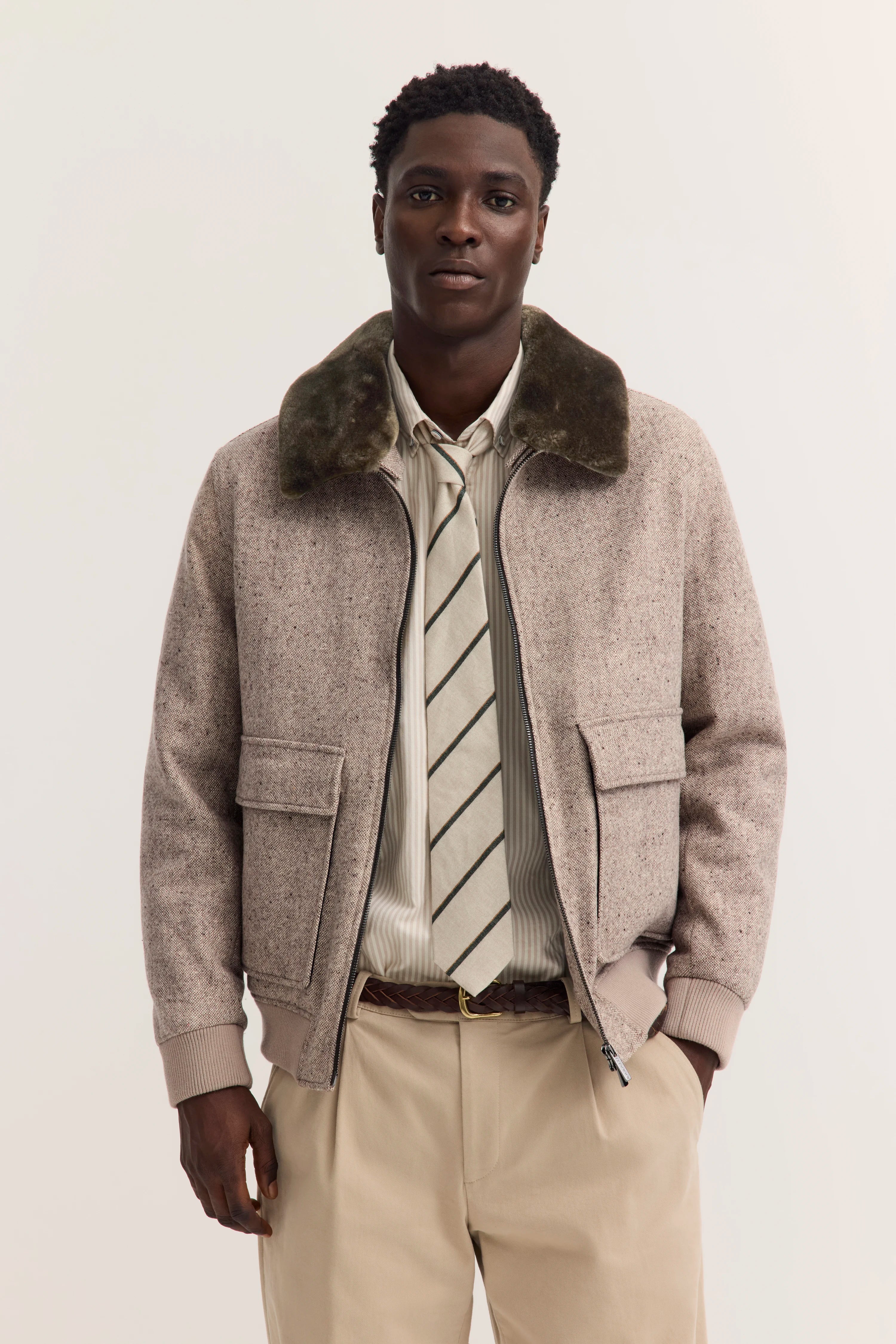 Bugatti Model in beiger Jacke, gestreiftem Hemd und Krawatte, legeres Posing.