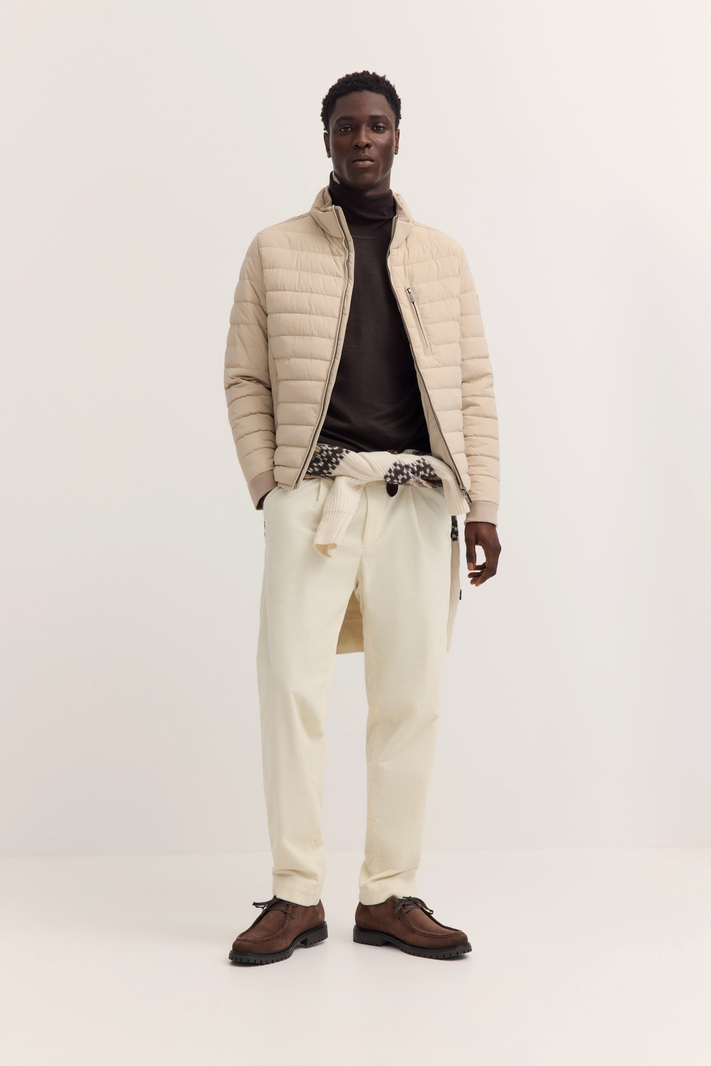 Beiges Steppjacke-Model, brauner Rollkragen, cremefarbene Hose, posierend, bugatti Stil.
