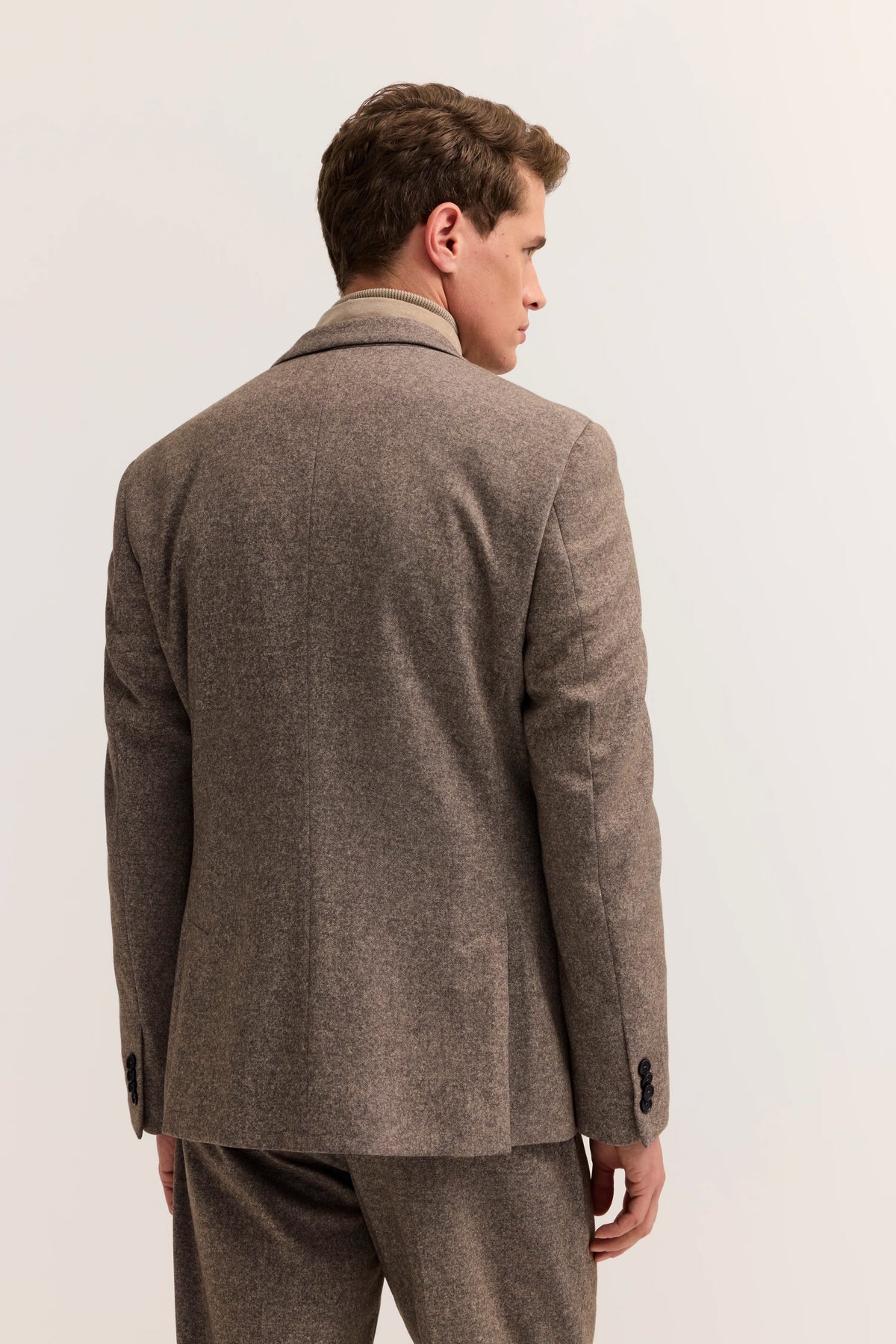Brauner Anzug mit Fischgrätmuster, Model von hinten, lässige Pose.