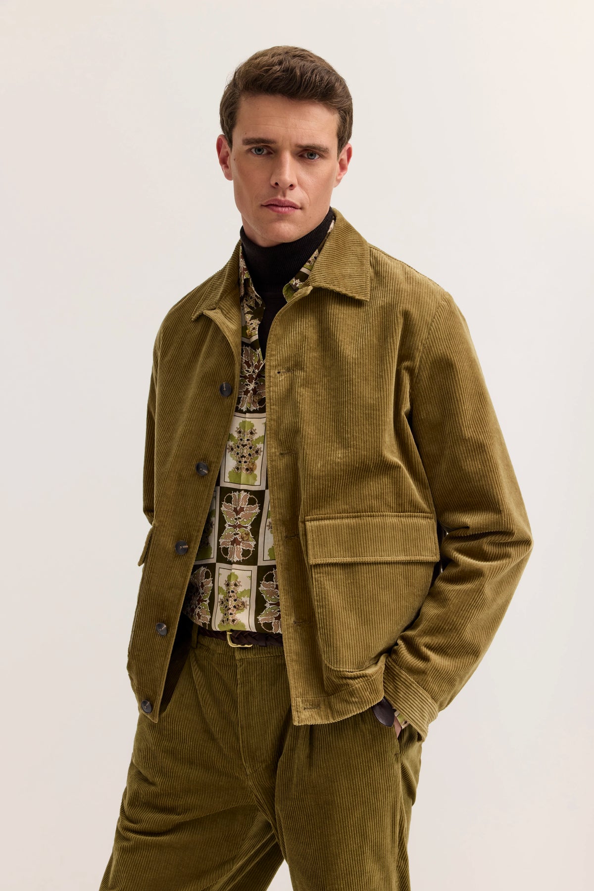 Model in olivgrünem Cordanzug mit gemustertem Hemd, gerade Haltung, stilvoller bugatti Look.