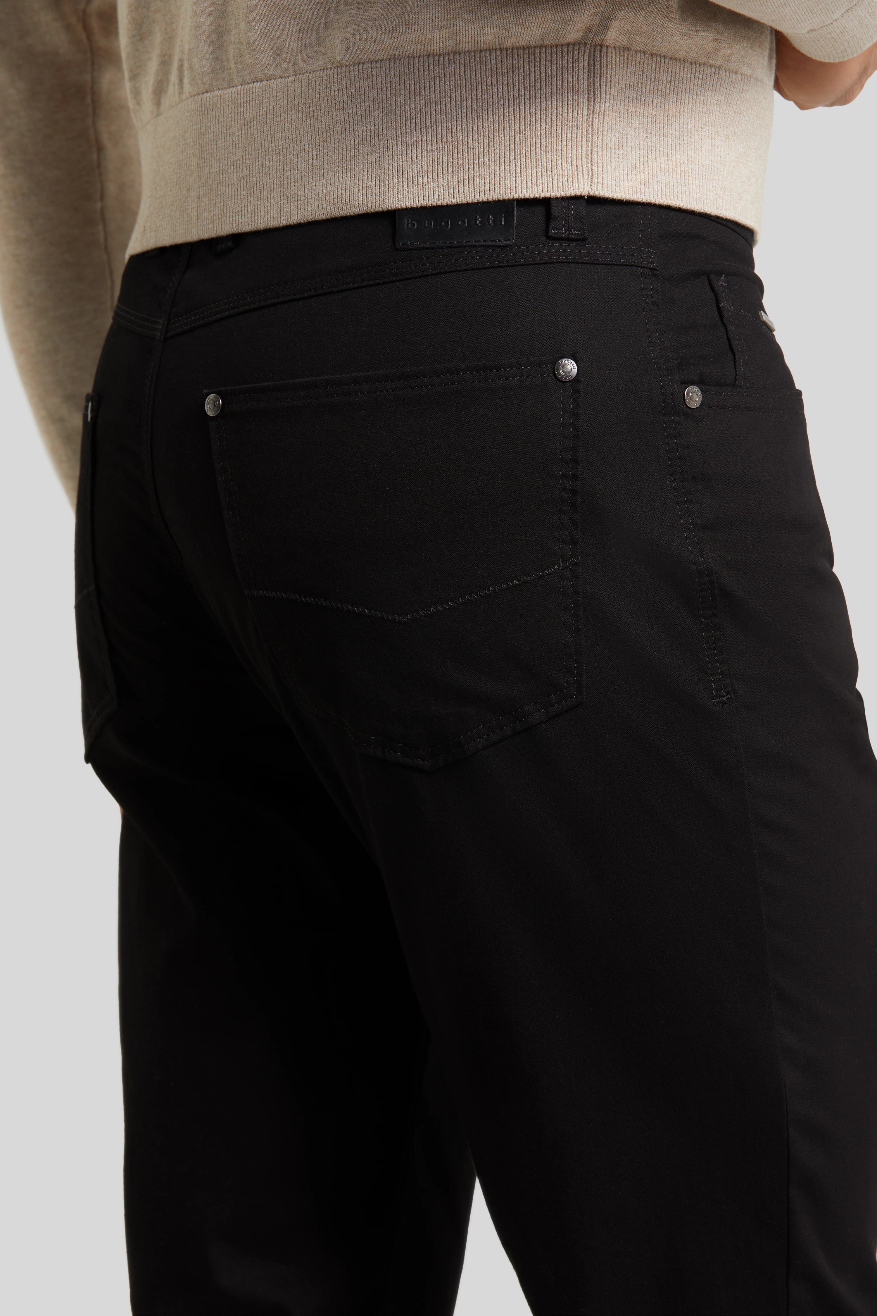 Schwarze bugatti Hose, Detailansicht der Rückseite, beige Oberteil, legeres Modelbild.