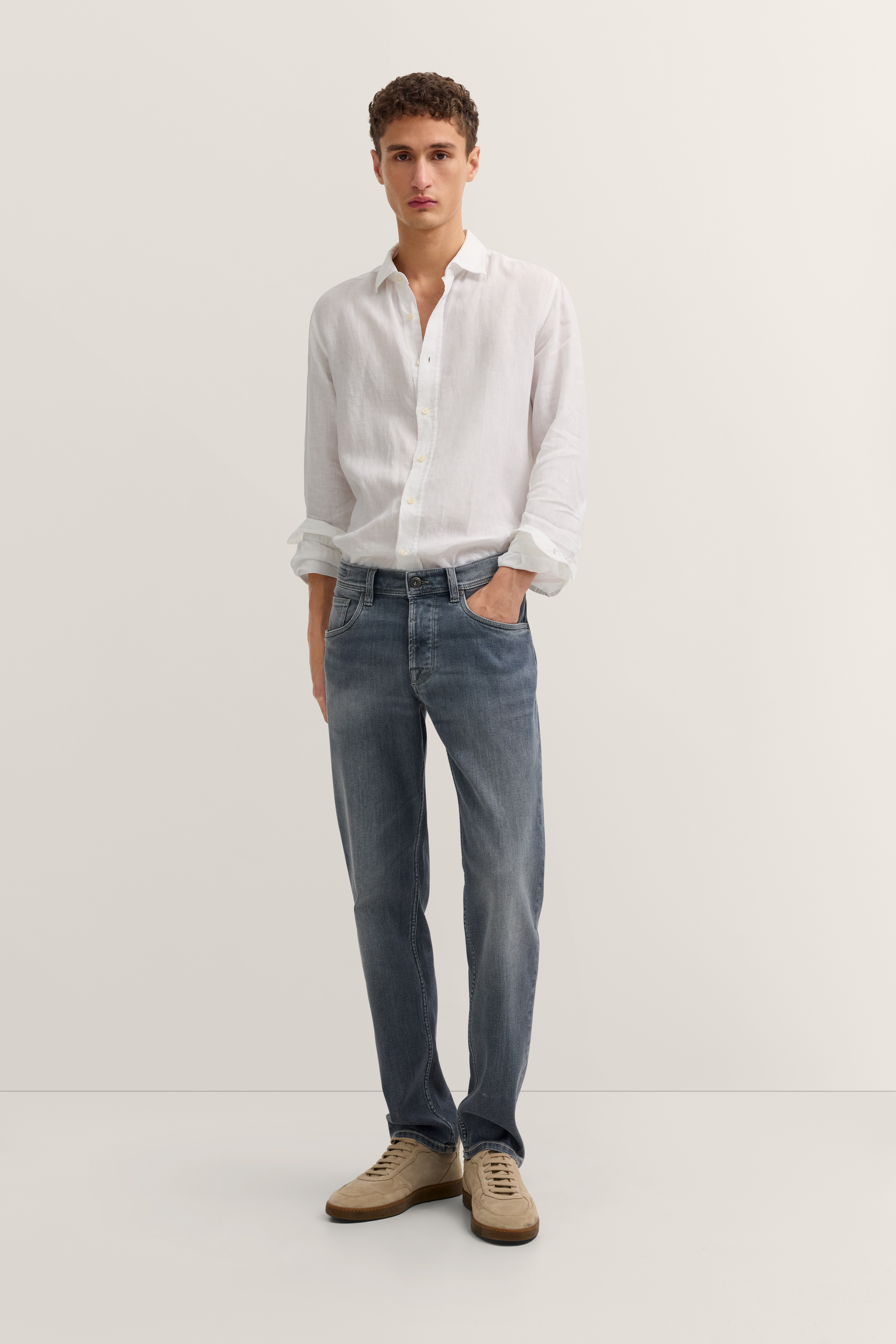 bugatti legeres Modelbild: Weißes Hemd, blaue Jeans, beigefarbene Schuhe, entspannte Rückansicht.